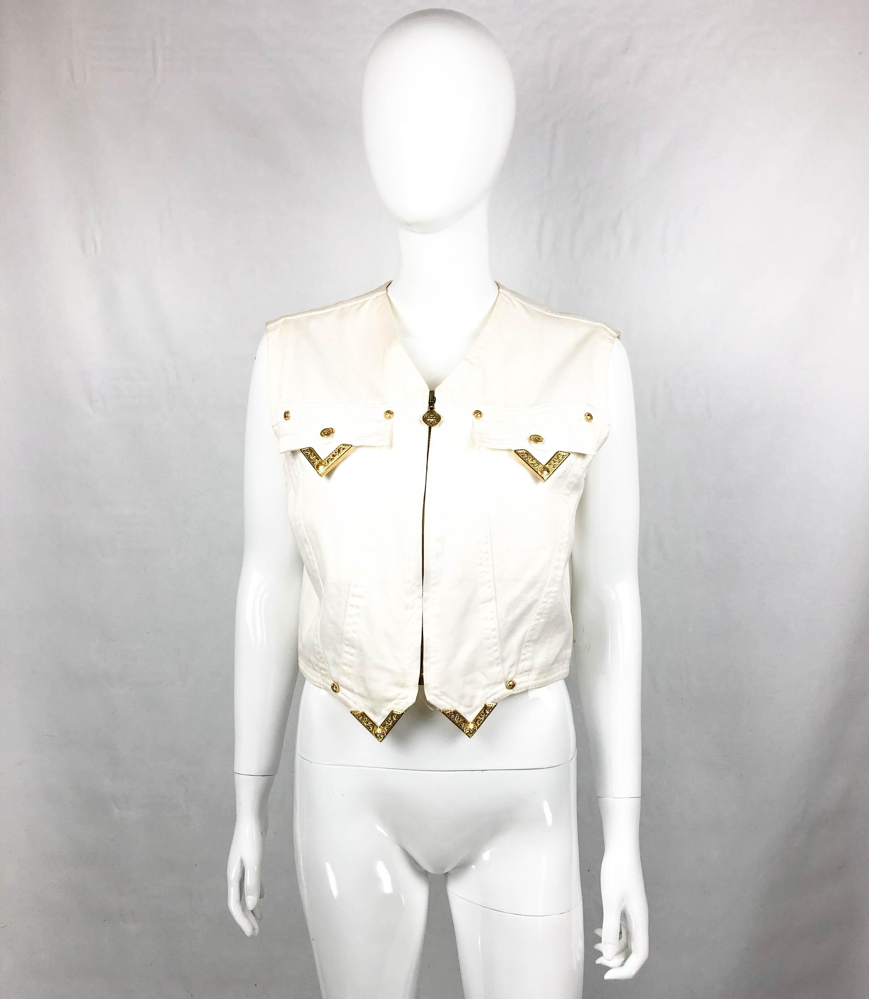 Vintage Gianni Versace White Denim Waistcoat. This gorgeous piece by Gianni Versace dates back from 1991. Bringing a western undertone, it is made in white denim and it has a zip closure. It features baroque inspired gilt tips on collar, hem and