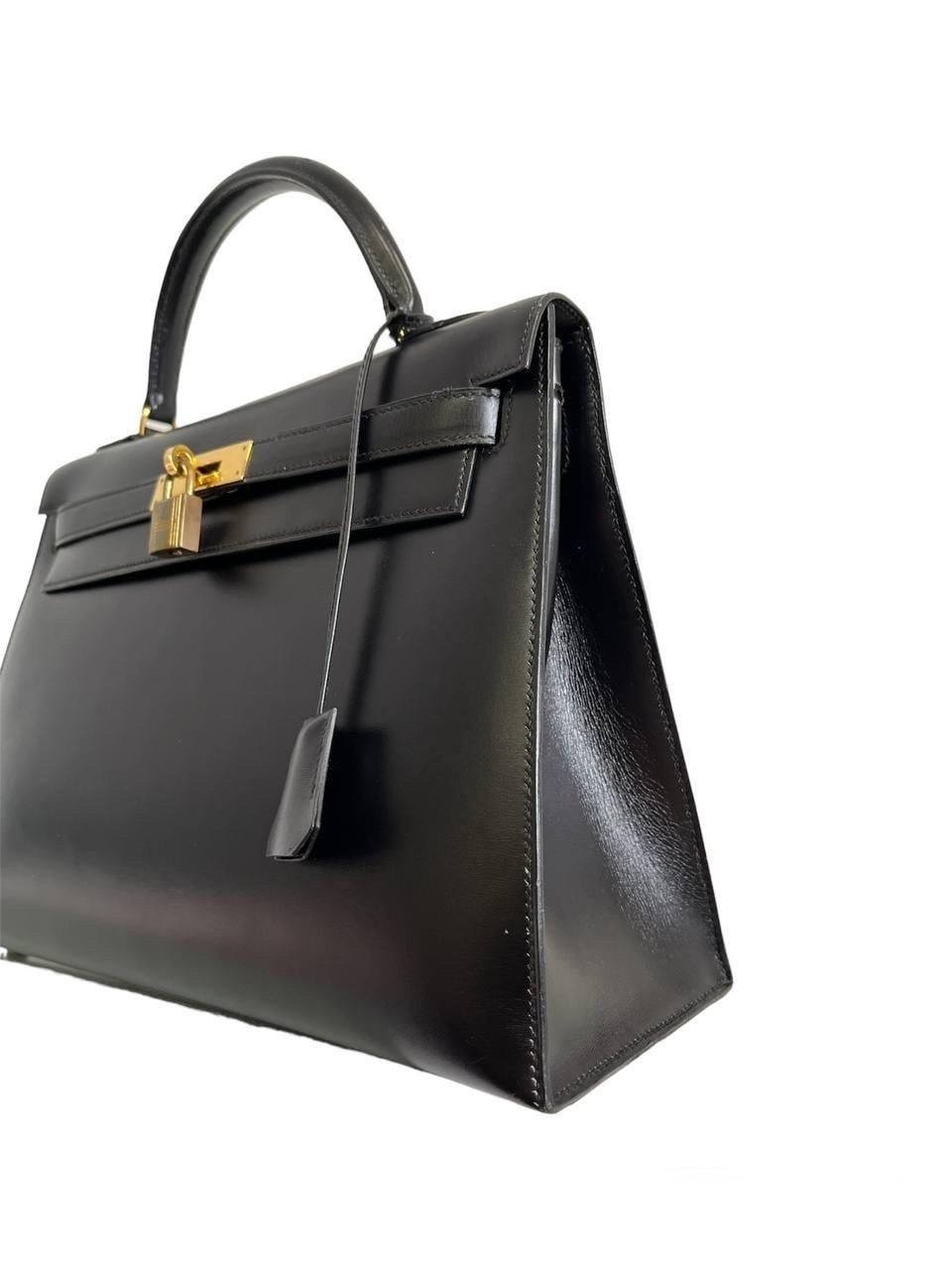 Bag by Hermès, Kelly model, size 32, made of Box Calf leather, rigid, smooth and shiny, in the Noir color, with gold-tone hardware. Equipped with a flap with interlocking closure with horizontal band, complete with padlock, clochette and keys.