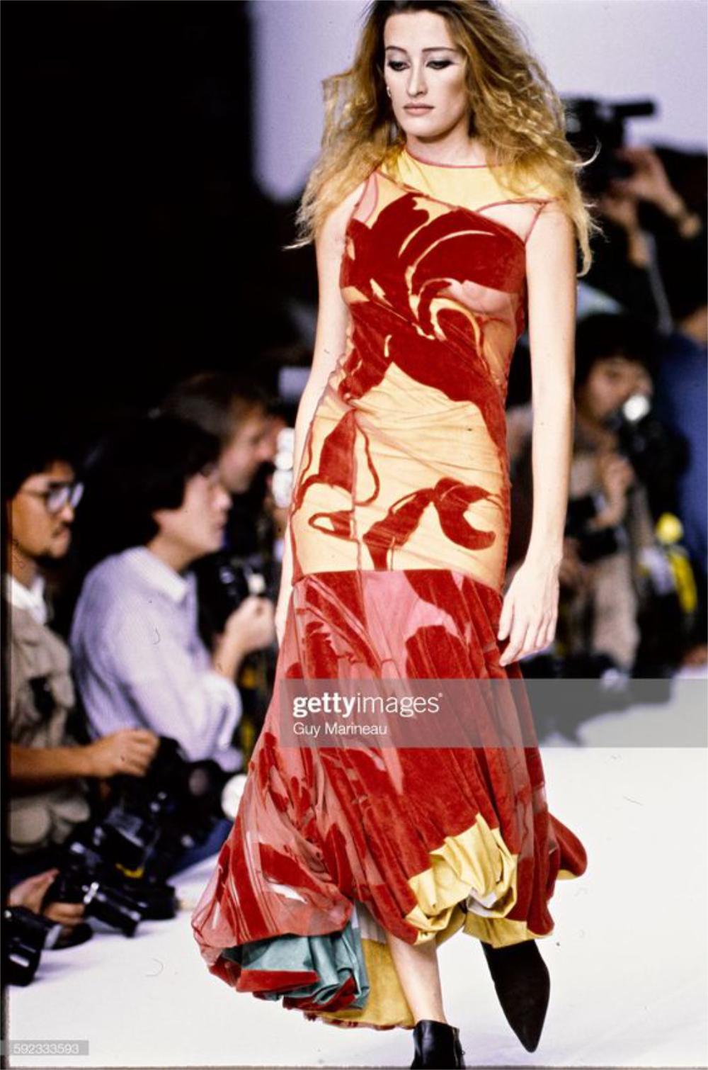 An incredibly rare and highly coveted John Galliano sheer red flocked velvet and lycra asymmetric bias-cut gown from his beloved 1991 spring/summer 'Honcho Woman' collection. As shown, the beautiful Marie Sophie Wilson walked down the runway in this