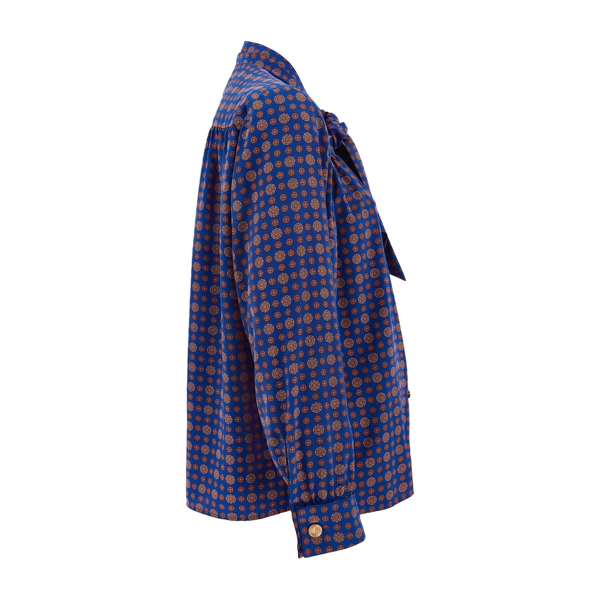 Made in France, this shirt was designed by Yves Saint Laurent in 1991 for his department store diffusion line Variation. Tailored from a vibrant high quality manmade crepe in French blue, it is detailed with a repeat pattern of Tudor roses in burnt