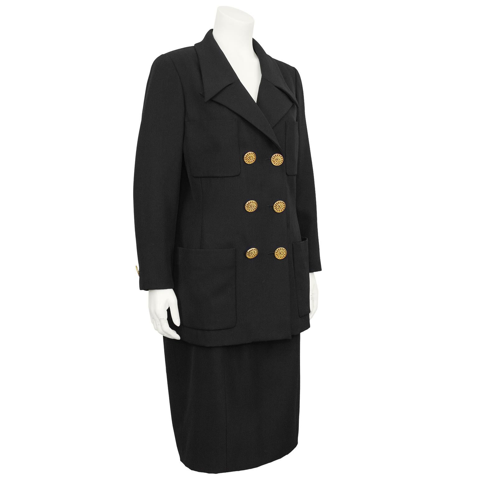 Chanel collection 29 black gabardine double breasted skirt suit. The jacket features large gold coiled chain buttons down the front with four square front patch pockets; similar to the placement on a classic Chanel jacket. The notched lapel has a