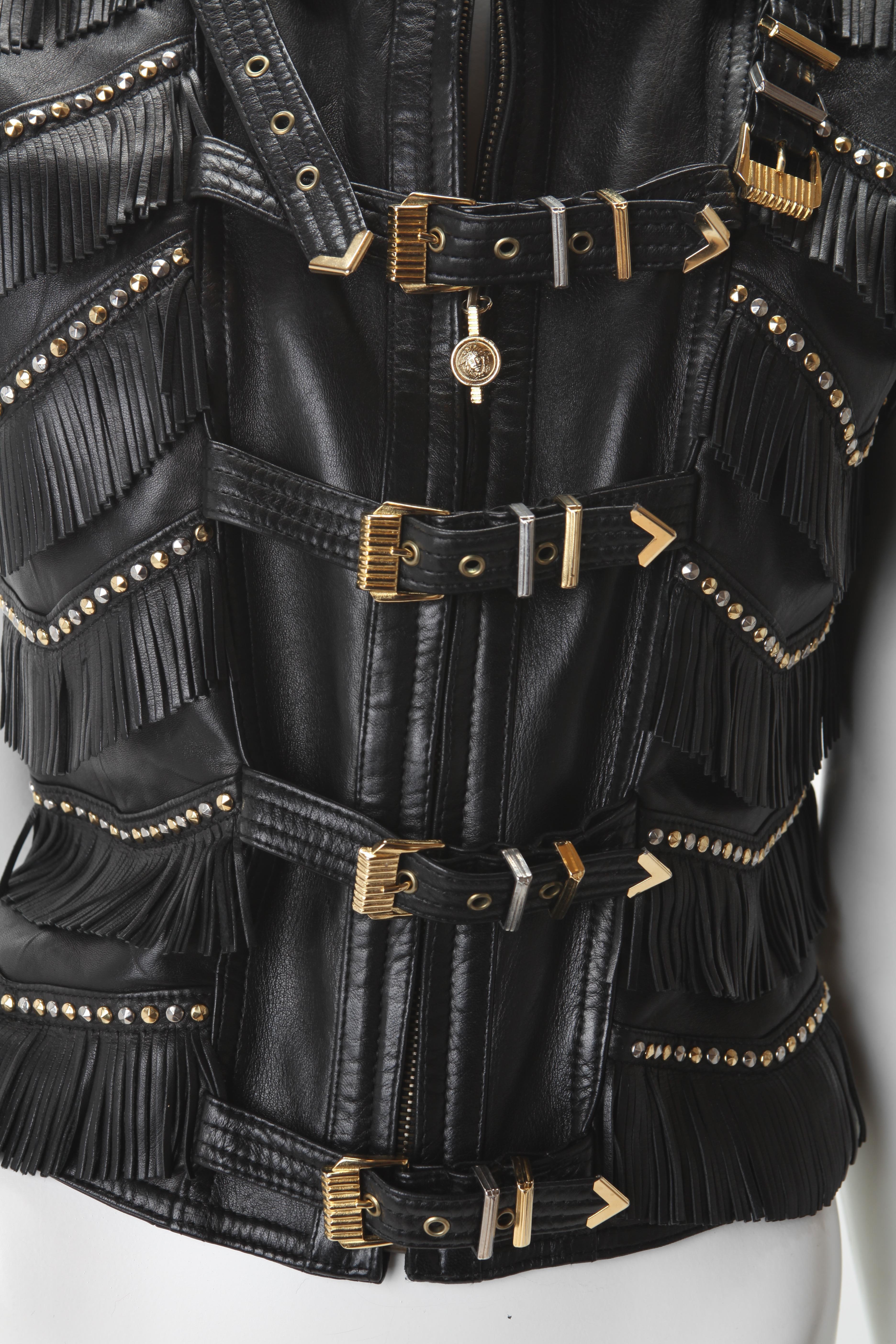 1992 Gianni Versace Black Leather Fringe Bondage Vest. Features silver and gold-tone hardware; Medusa medallion zipper pull. Tiered fringe with studded accents. 100% Leather with rayon lining.  size 4/6