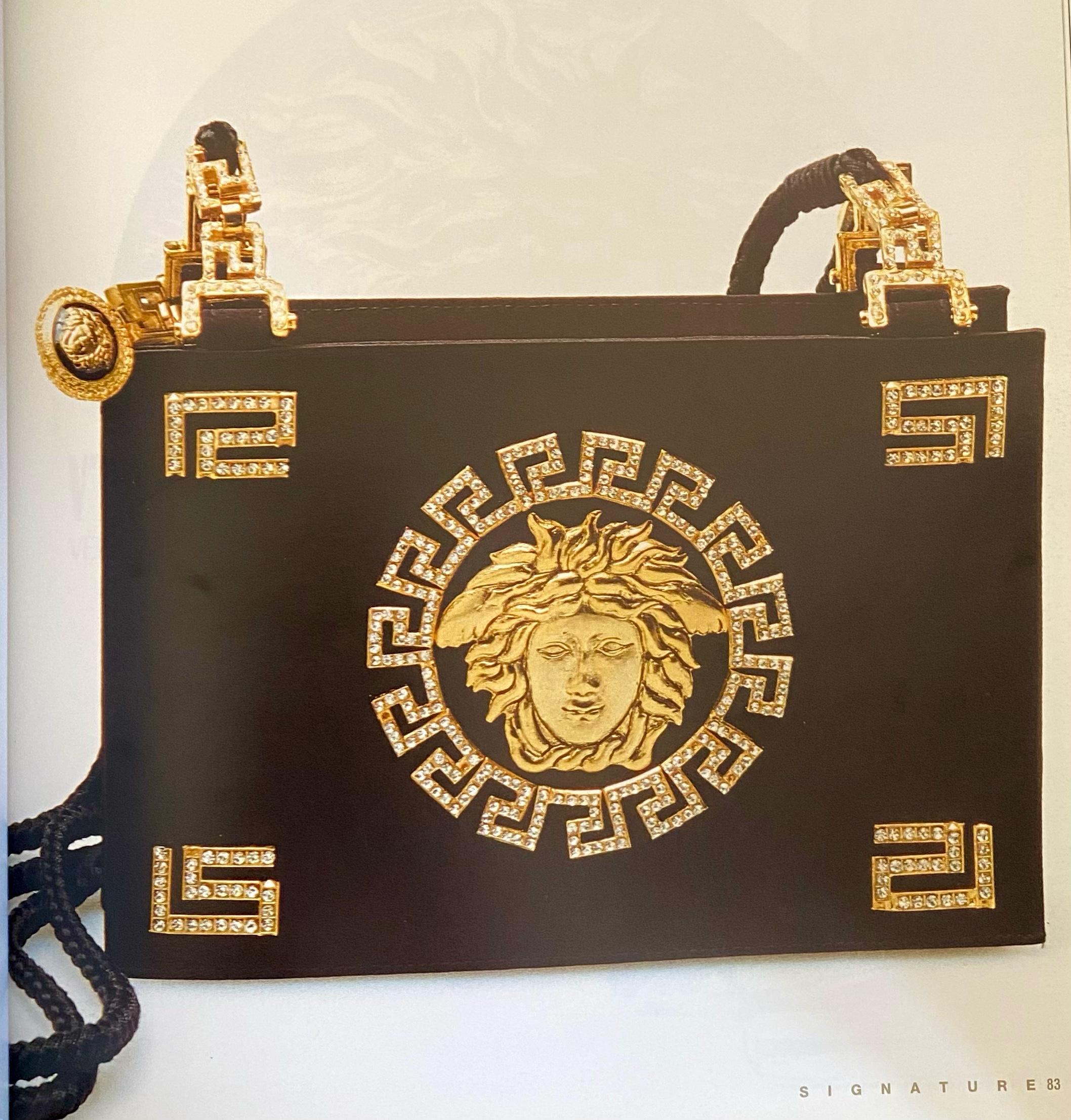 Made of gorgeous black silk satin and embellished bag with a large iconic gold Medusa logo, this bag is classically Versace. Gold and crystal Greek Key embellishments are seen throughout the bag, including on the zipper which is constructed of a