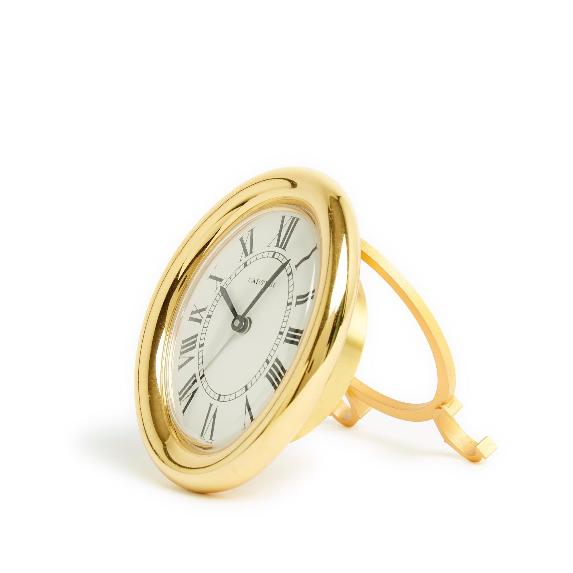 Cartier alarm clock, Baignoire model, in gold-plated metal, quartz movement, white dial with railway track and Roman numerals, 2 crowns on the back for setting the time and alarm and 1 push button for turning the clock on and off alarm clock, matt