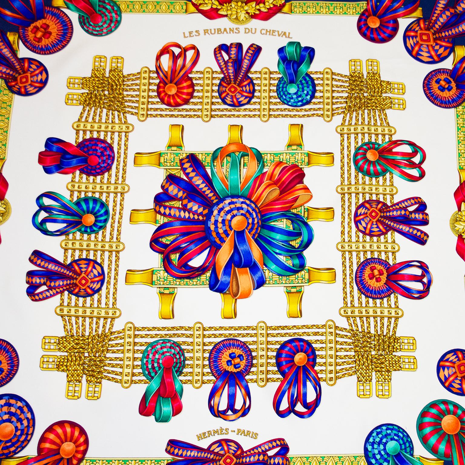 Beautiful Hermes 'Les Rubans du Cheval' silk scarf. Original silk screen design circa 1993 by Joachim Metz. The scarf features a colourful array of equestrian ribbons over a white background with a navy blue border. 100% silk. Hand rolled hem and