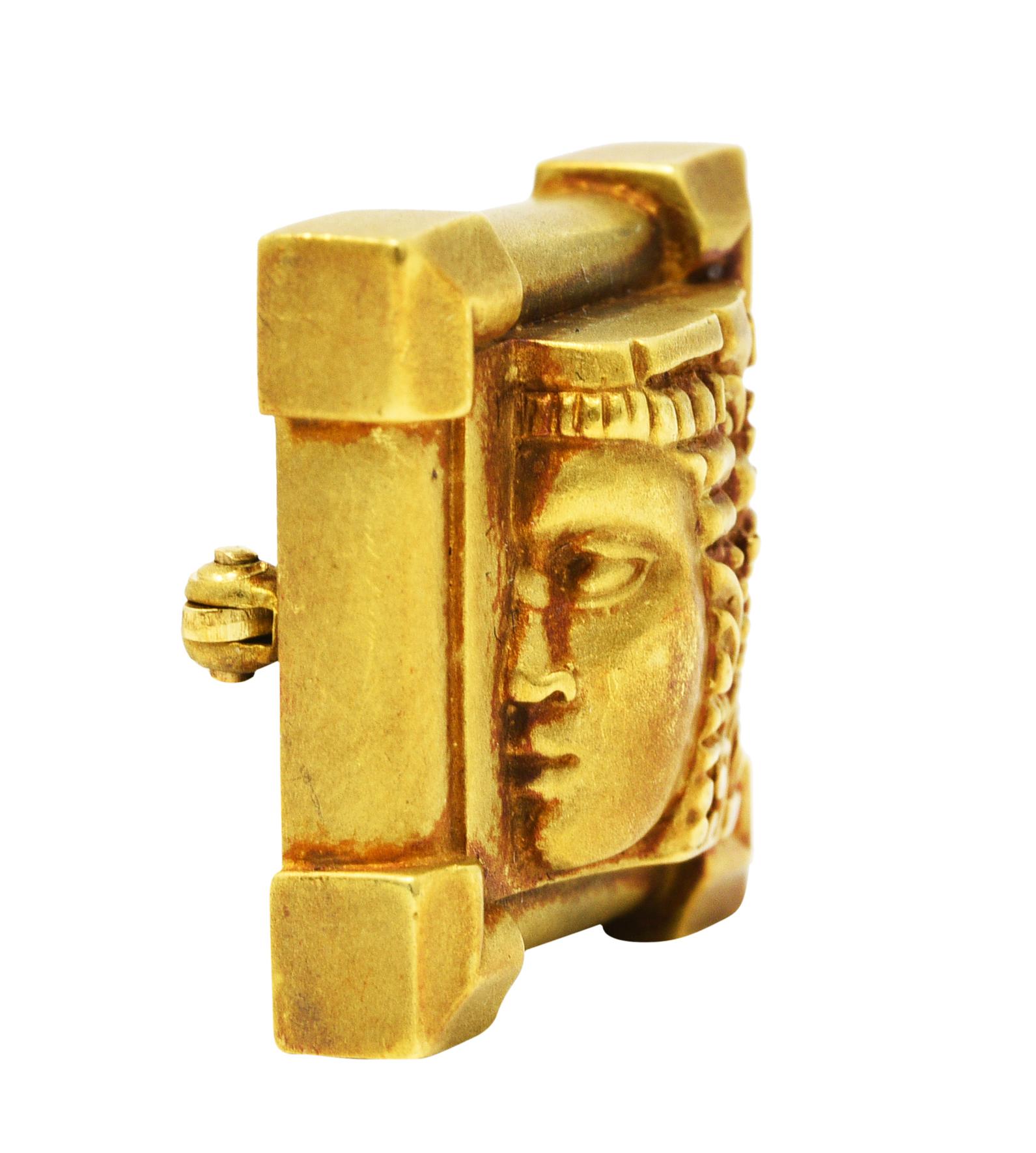 Square shaped brooch depicts a highly rendered female profile that protrudes forward

Headdress is deeply engraved with geometric motifs

With a structured border emphasized at each corner

Completed by a matte finish and a pin stem with locking