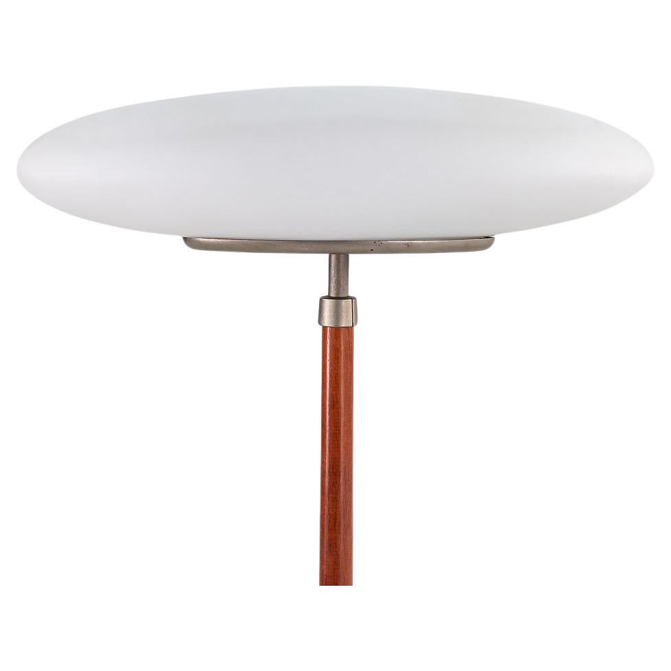 This is a PAO Floor Lamp, initially designed by Matteo Thun for Arteluce in Italy in 1993. This example was produced in the mid-1990s. It features a frosted glass shade with an opaline blown-glass diffuser, and it has a cherry wood base. The piece