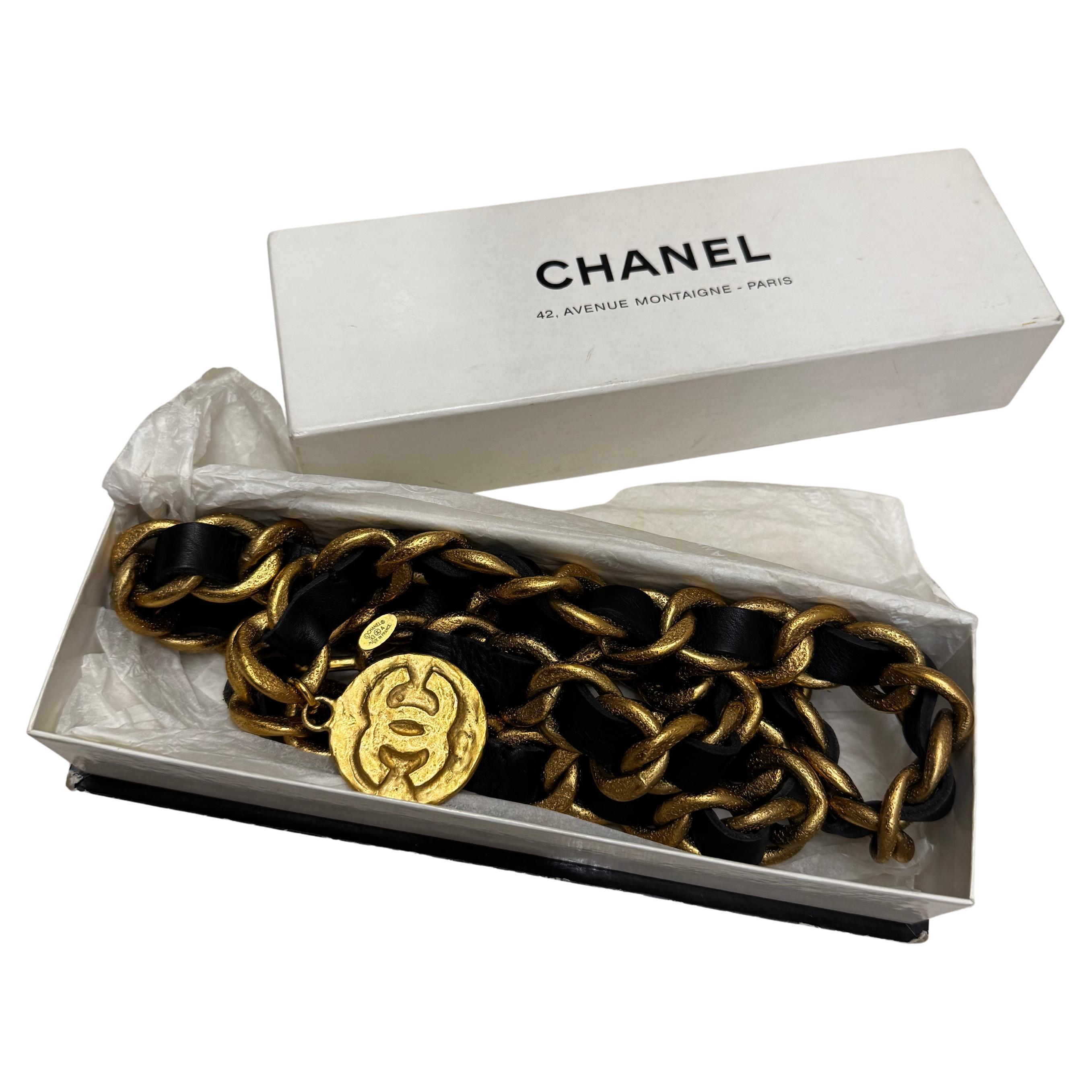 Cette ceinture en chaîne massive vintage Chanel est faite d'une solide chaîne texturée dorée entrelacée de cuir noir, d'une double chaîne drapée et d'un médaillon CC de style byzantin en guise de breloque. Vu sur la piste SS 1993. Estampillé CHANEL