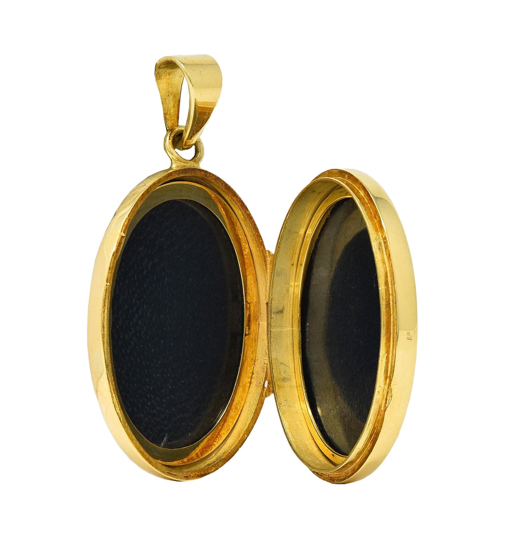 Designed and an oval-shaped locket pendant suspending from a tapered bale
Front of locket is engraved with a scrolling feather plumage motif 
Accented by floral motif and zig-zag texture detailing
Opens on a hinge to reveal two recessed oval frames