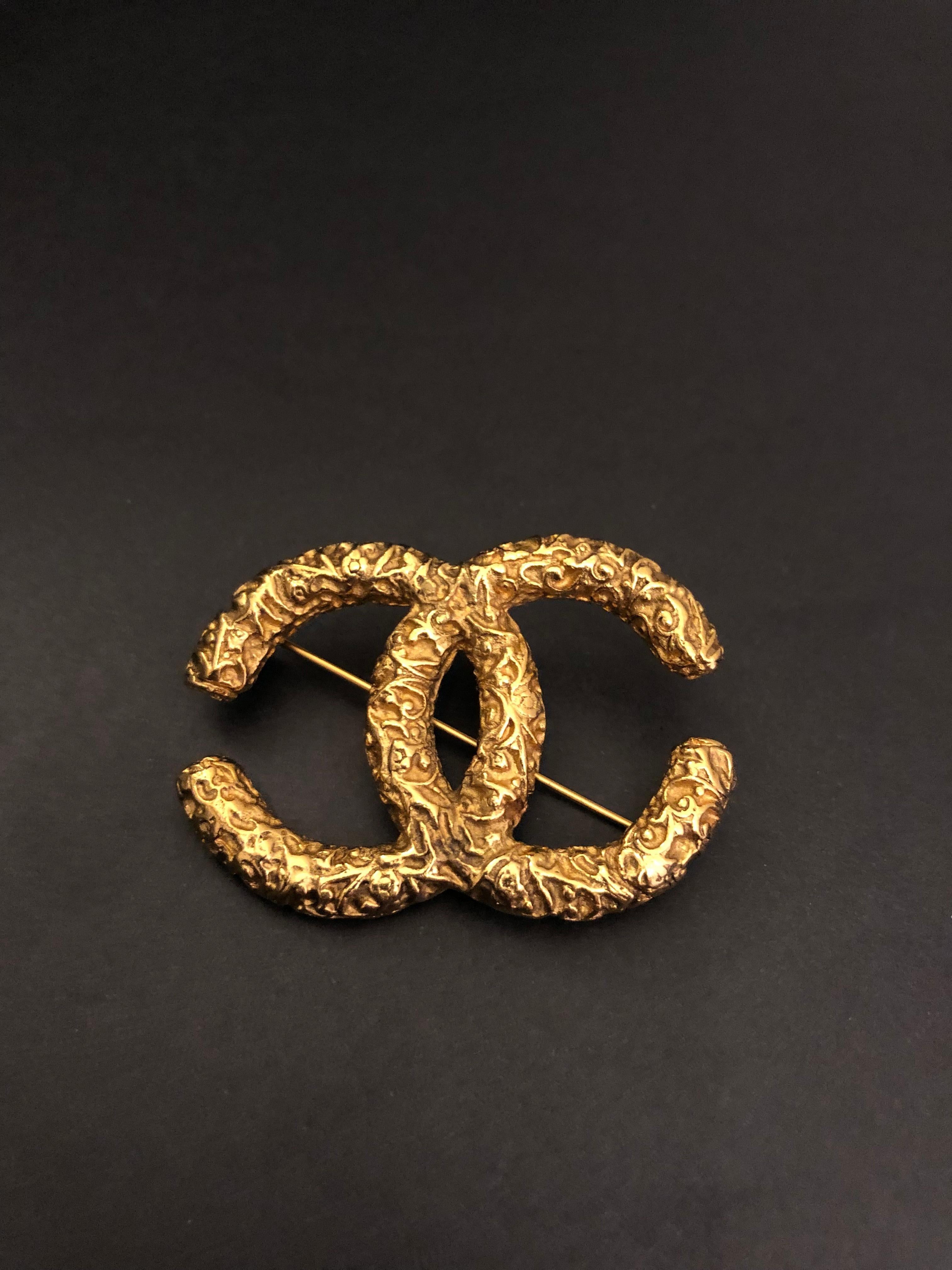 1993 CHANEL gold toned chain in floral textured intertwined CC motif. Stamped 93A made in France. Measures approximately 5.1 x 3.6 cm. Comes with box. 

Condition: Minor marks on the back. Generally in very good condition.