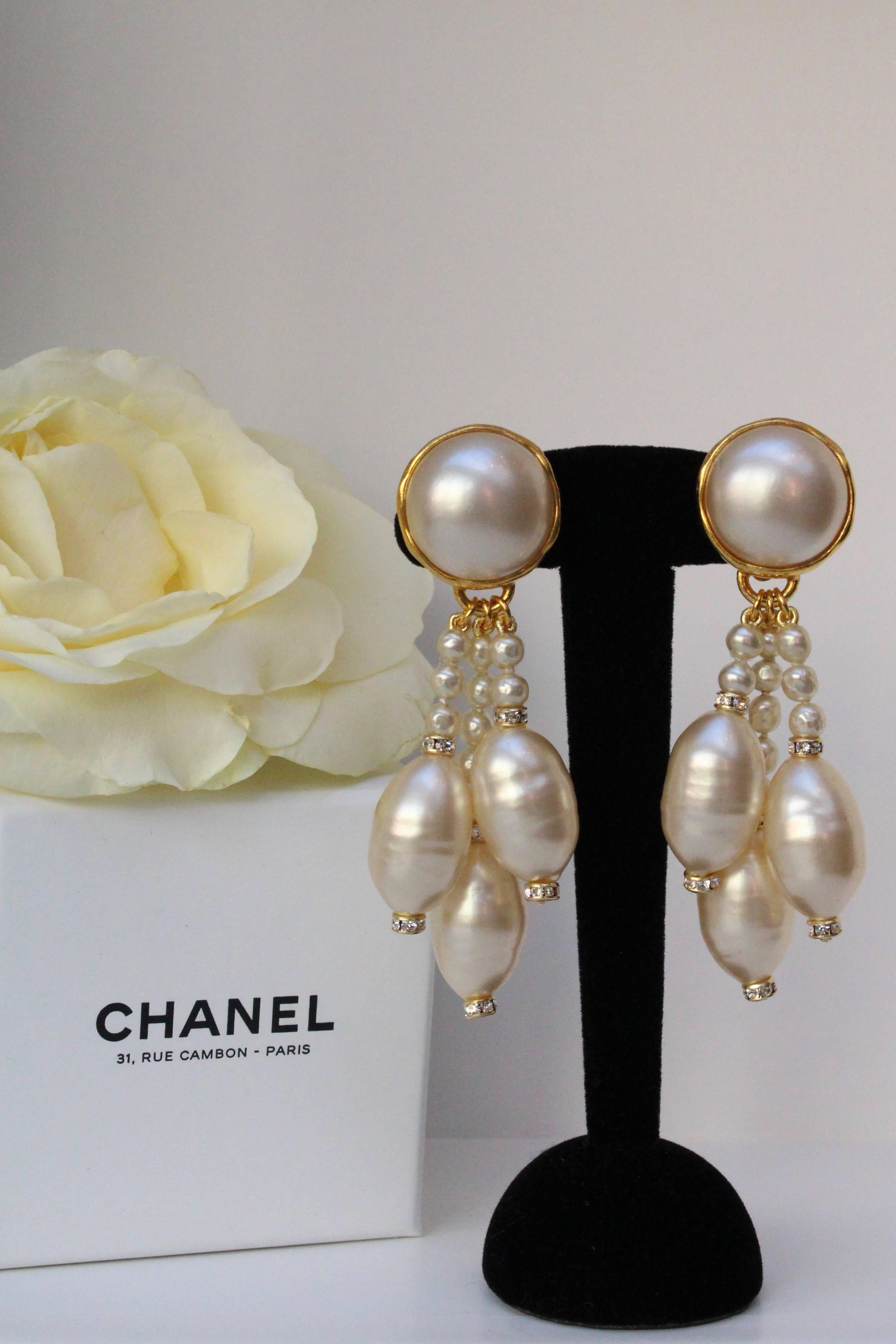 CHANEL (Made in France) Beautiful drop earrings comprised of a pearly cabochon from which dangle a series of small pearly beads ending with an olive-shaped pearly bead underlined with two Swarovski crystal spacers.

Signed at back.

1994 Fall –