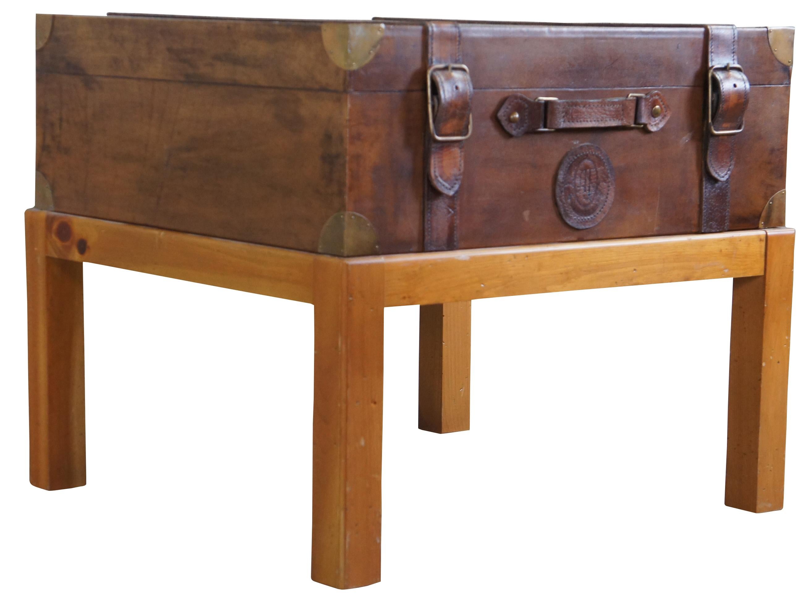 Vintage 1994 leather steam trunk on Pine stand. Features straps and brass covered corners. Trunk does not open. Measure: 25