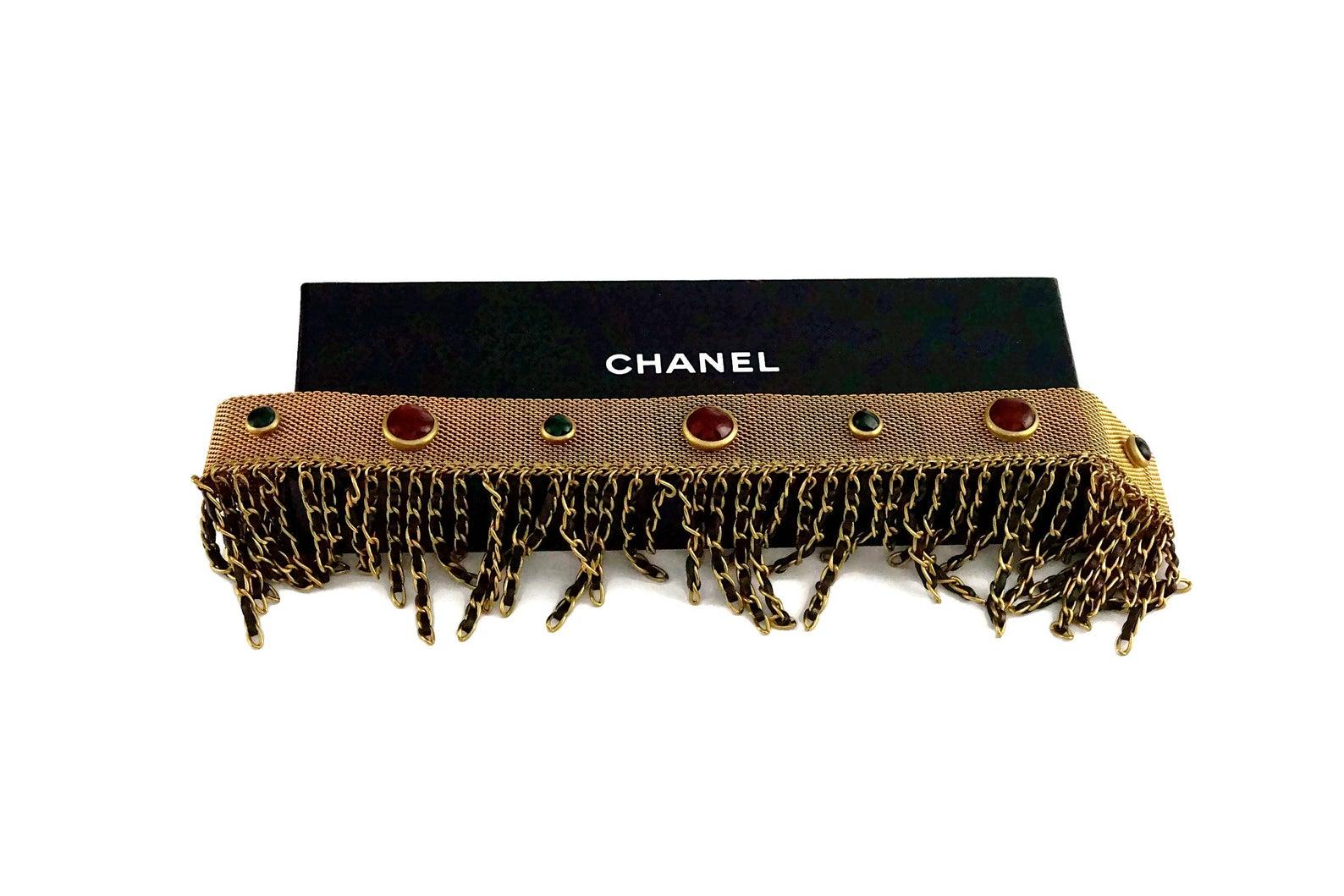 Features:
- 100% Authentic CHANEL from 1994 Autumn Collection.
- Mesh choker with Chanel's iconic red and green gripoix/ poured glass.
- Iconic leather chain fringes.
- Gold tone hardware.
- Snap button closure.
- Signed CHANEL 94 CC A Made in