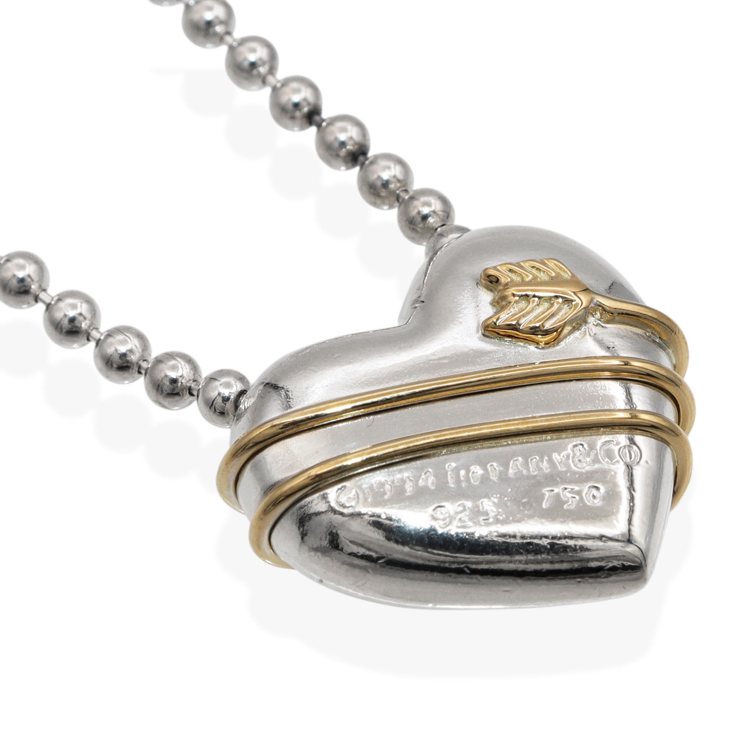 Questa elegante collana di Tiffany & Co. è caratterizzata da un ciondolo a forma di cuore in argento sterling lucidato e da un'elegante fascia in oro giallo 18 carati che crea un sorprendente contrasto di metalli. Il ciondolo è sospeso a una