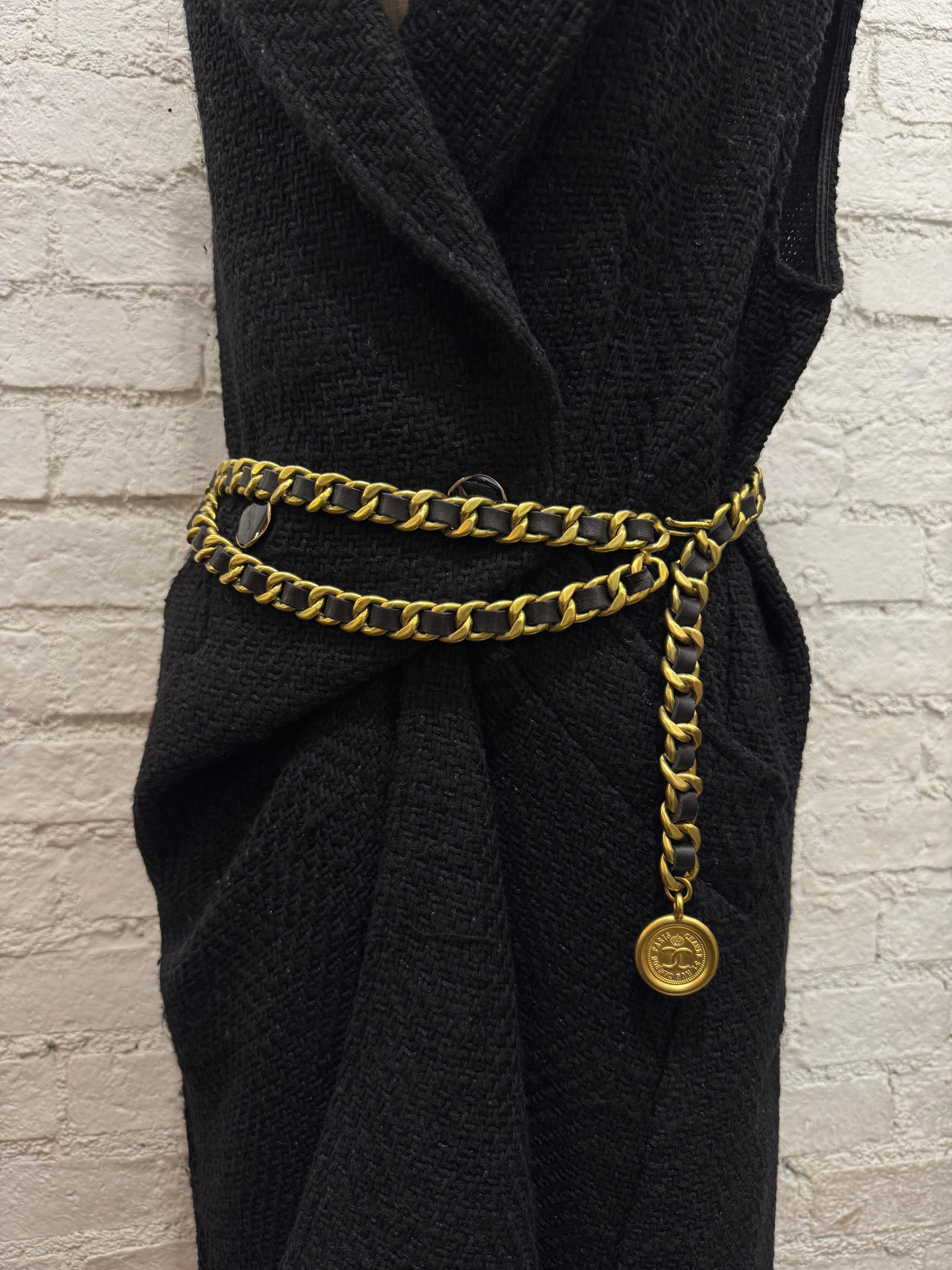 Cette exquise ceinture en cuir CHANEL vintage est composée de solides chaînes dorées mates entrelacées de cuir d'agneau noir, d'une double chaîne drapée sur le devant et d'une breloque en forme de pièce de monnaie COCO CHANEL. Estampillé 94A CHANEL