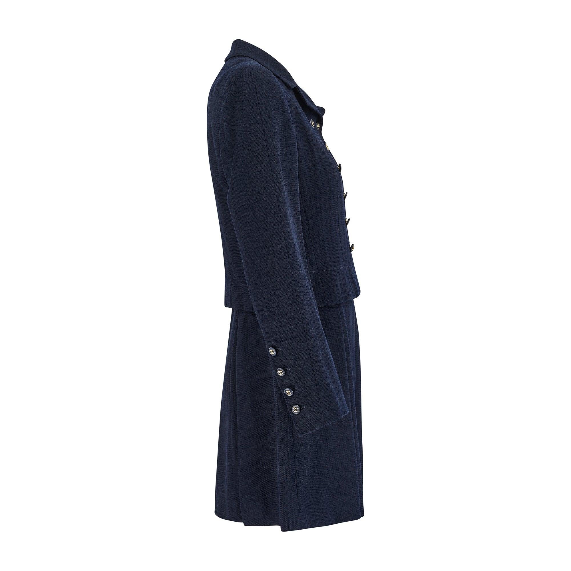 Dieser elegante cremefarbene und marineblaue Anzug wurde von Chanel für seine Frühjahrskollektion 1995 entworfen und in Frankreich hergestellt.  Der elegante, umgekehrte Zweireiher war auf der Laufstegpräsentation auf Anzügen, Hosen, Jacken und