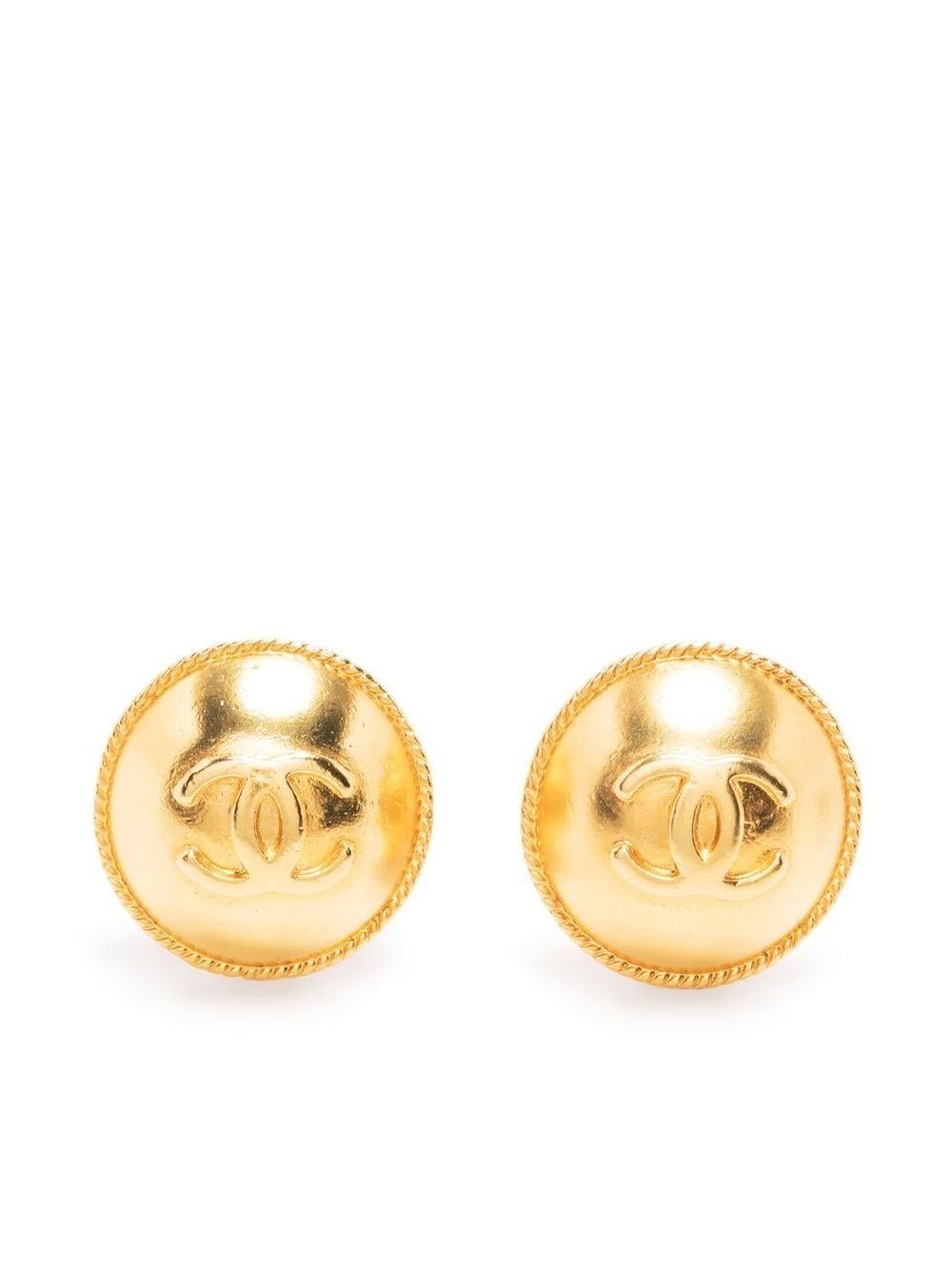 goldfarbene Chanel-Ohrringe zum Anstecken aus dem Jahr 1995 mit folgendem Design: goldfarbenes Logo, Clipverschluss, hintere Plakette mit entkerntem Chanel-Logo am Clip. 
Diese Ohrringe werden als Paar geliefert.
Etwa 1995
Durchmesser: 0,8 Zoll (2