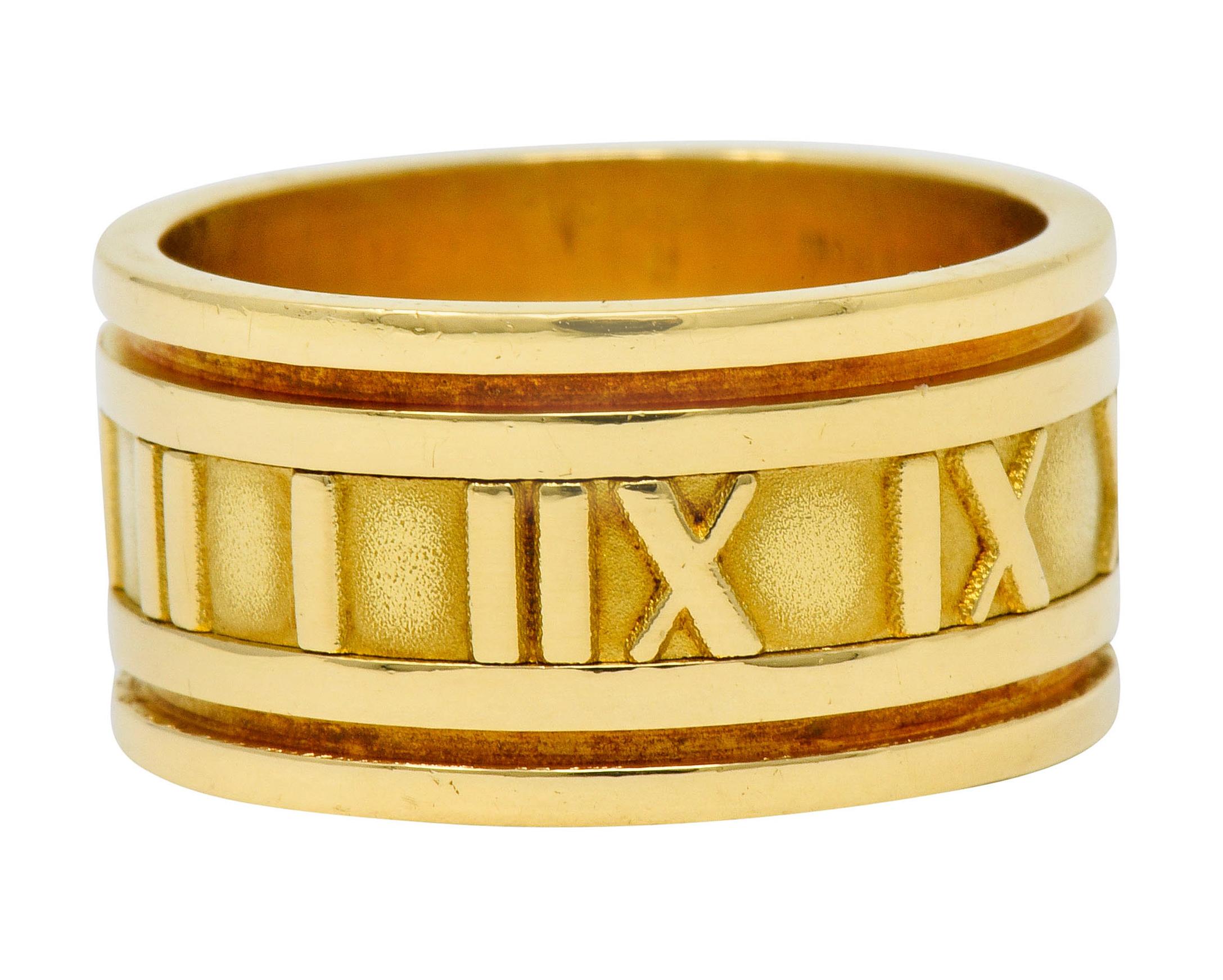 Wide band ring centering raised and brightly polished Roman numerals against a matte gold background

Flanked by deeply grooved channels

Fully signed Tiffany & Co. Italy 1995

Stamped 750 for 18 karat gold

From the vintage 1990's Atlas