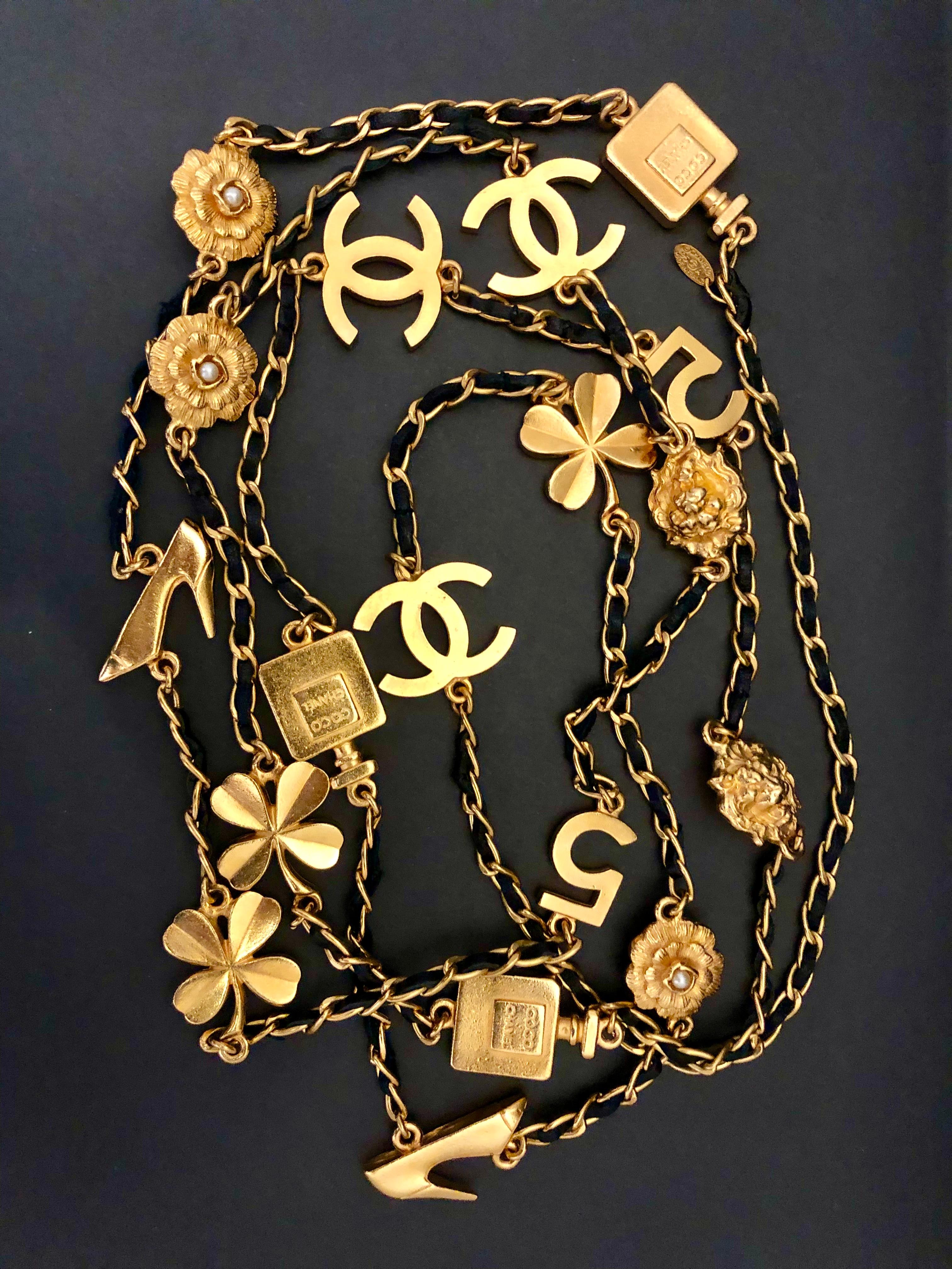 This vintage CHANEL long chain necklace is crafted of gold toned chain interlaced with black leather featuring 18 Chanel’s iconic CC Camellia No.5 Clover Lion motifs. Slip on style. Stamped Chanel 95A made in France. Measures approximately 190 cm in