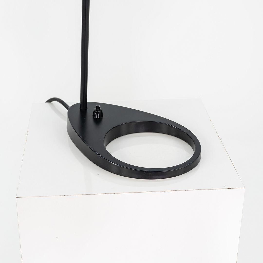 This is an AJ Lamp, originally designed by Arne Jacobsen for Louis Poulsen in 1957. This particular example dates to 1996 and was produced in Denmark. The lamp features a black enameled steel shade with a distinctive asymmetrical form, mounted on a