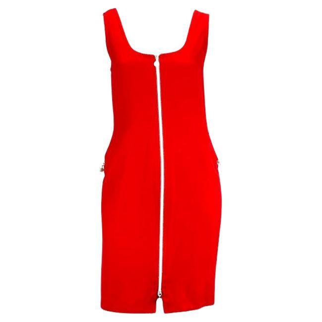 Présentation d'une robe rouge vif zippée Gianni Versace, dessinée par Gianni Versace. Datant de 1996, cette robe présente un large décolleté, des poches zippées sur les hanches et une grande fermeture à glissière dans le dos. La robe est complétée