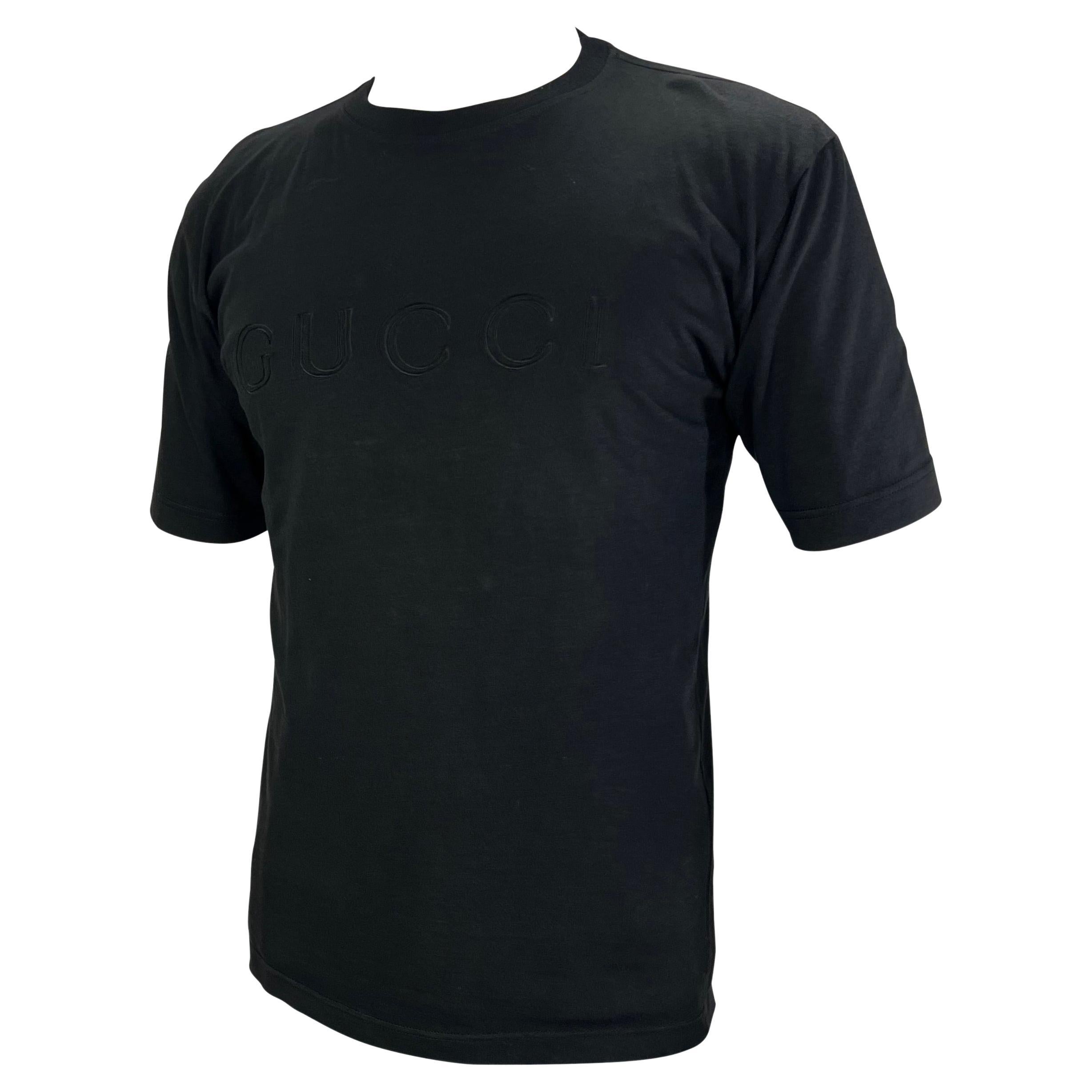 Présentation d'un t-shirt noir avec logo Gucci, dessiné par Tom Ford. Datant de 1996, ce t-shirt noir est parfaitement rehaussé par la présence de Gucci en toutes lettres sur la poitrine. Cette chemise Gucci by Tom Ford incontournable est la pièce