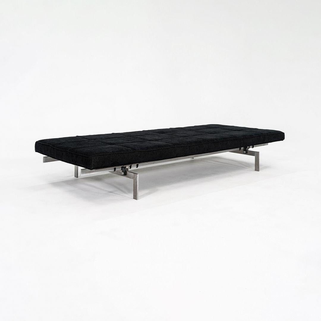 Il s'agit d'un lit de jour PK80, conçu à l'origine par Poul Kjaerholm en 1957 et produit par Fritz Hansen. Cet exemple particulier a été fabriqué en 1996. Il présente une silhouette minimaliste avec un coussin plat et rectangulaire tapissé de tissu
