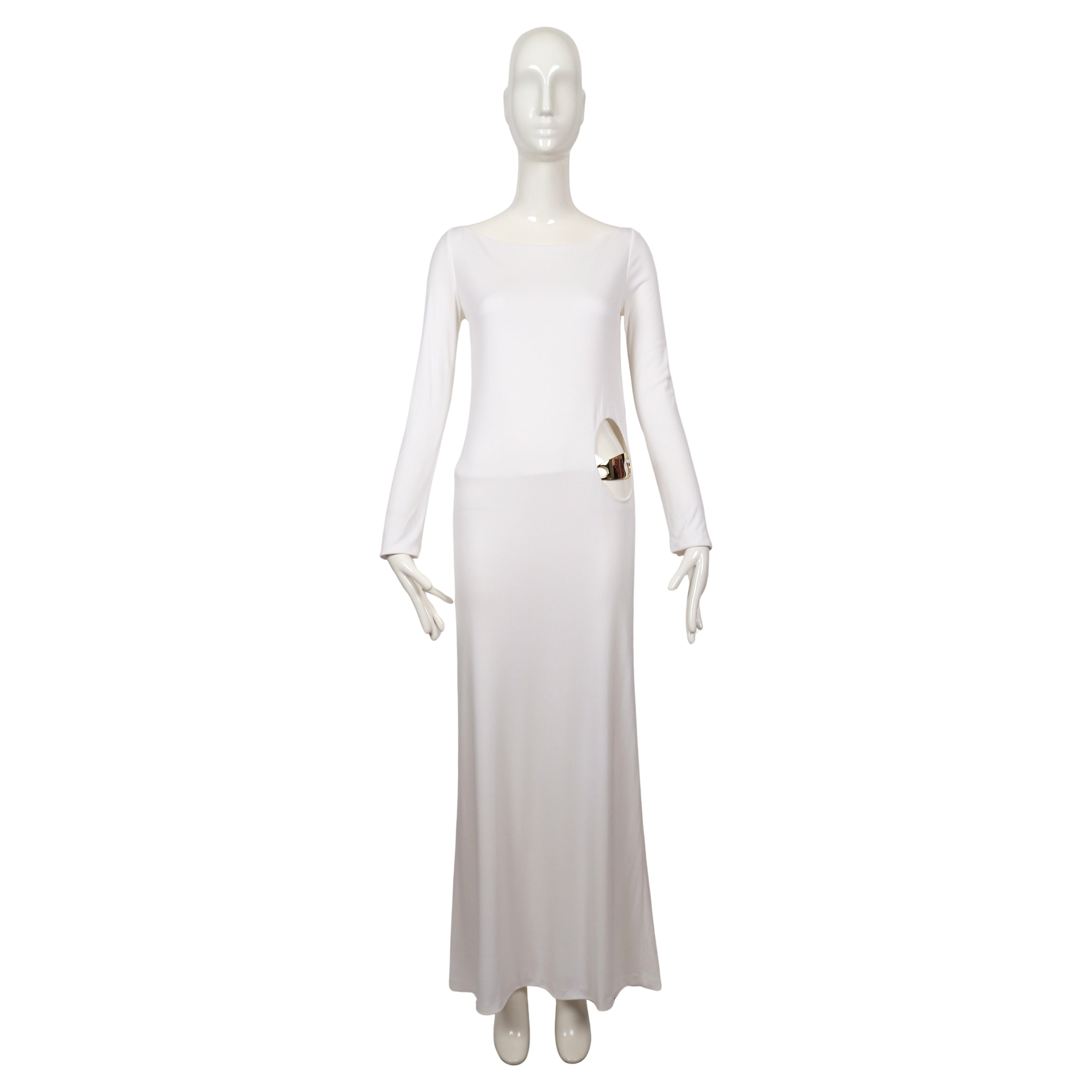 Iconic and important white jersey evening gown with circular hip cut out and belt with gold buckle designed by Tom Ford for Gucci dating to fall of 1996. This dress was featured on the 1996 fall runway, the fall 1996 ad campaign, as well as in