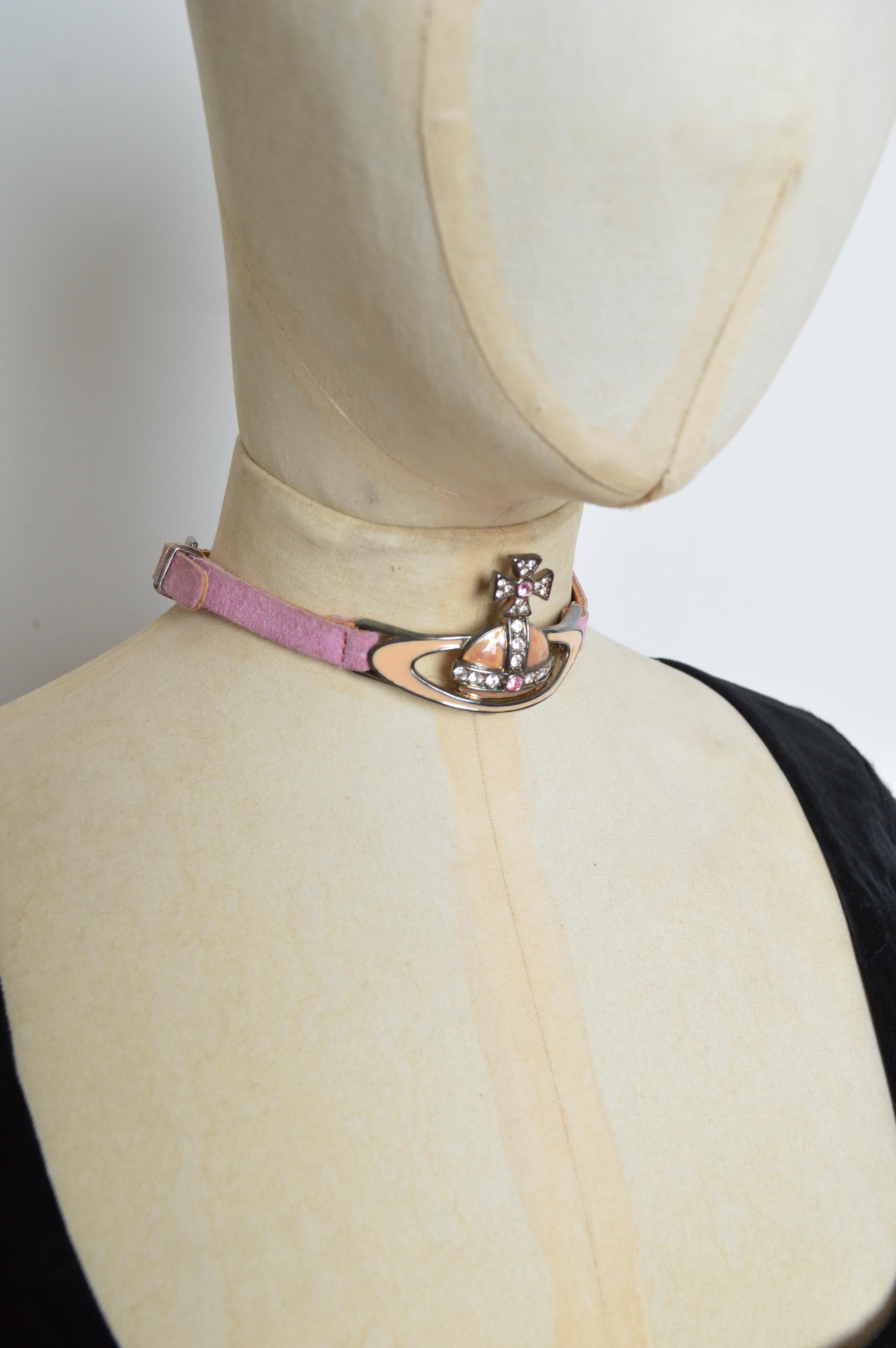 A Rare 1996 Vivienne Westwood Orb choker with rhinestone and enamel detailing. Crafted from pink suede with an adjustable silver-tone metal buckle fasten. 
Measurements are provided in Inches;
Length; 13’ - 14.5’’ Adjustable
Orb Dimensions; 1.75’’