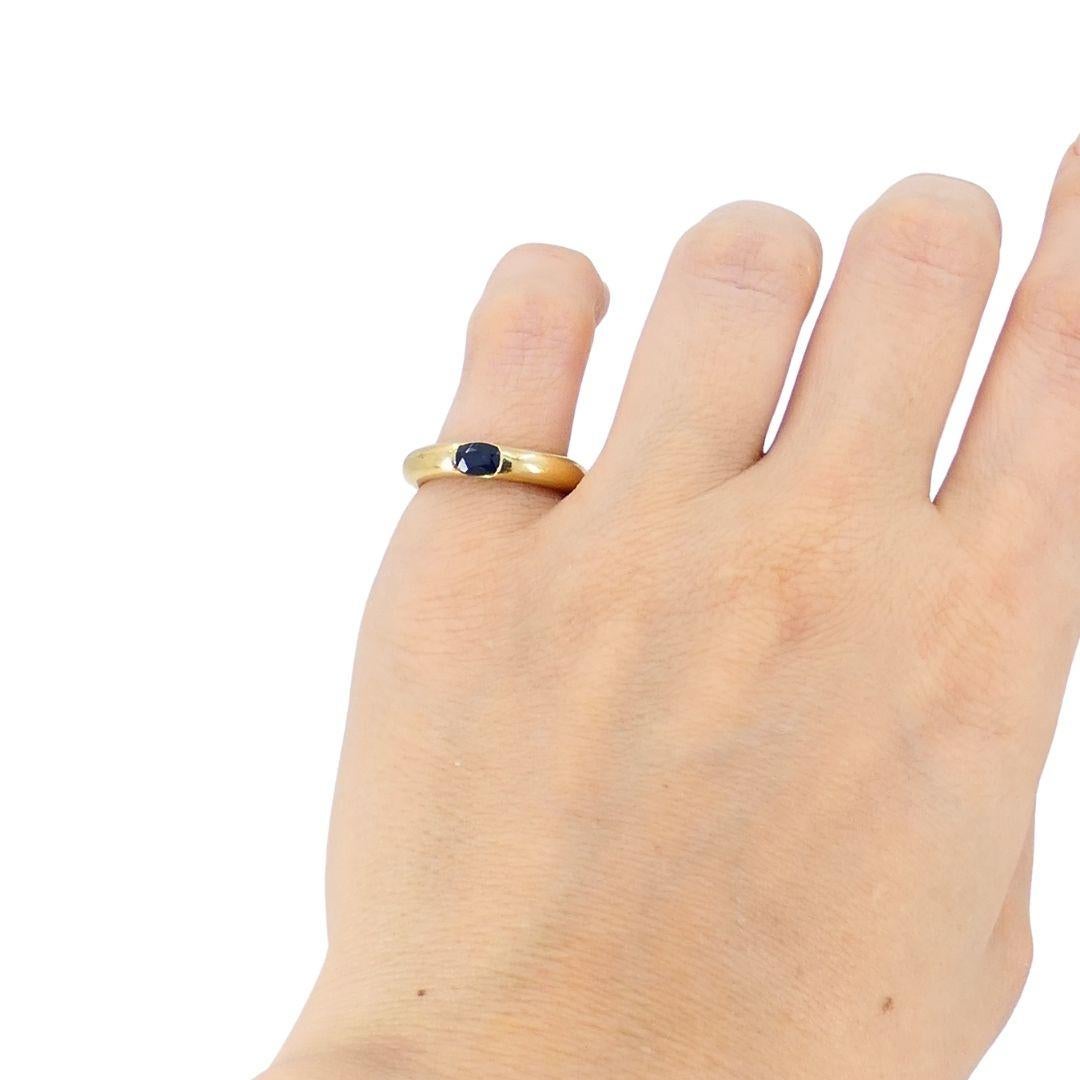 Este anillo elipse de Cartier está elaborado en oro amarillo de 18 quilates y presenta un zafiro azul engastado en su centro. El anillo tiene una elegante banda redondeada que mide 1/8