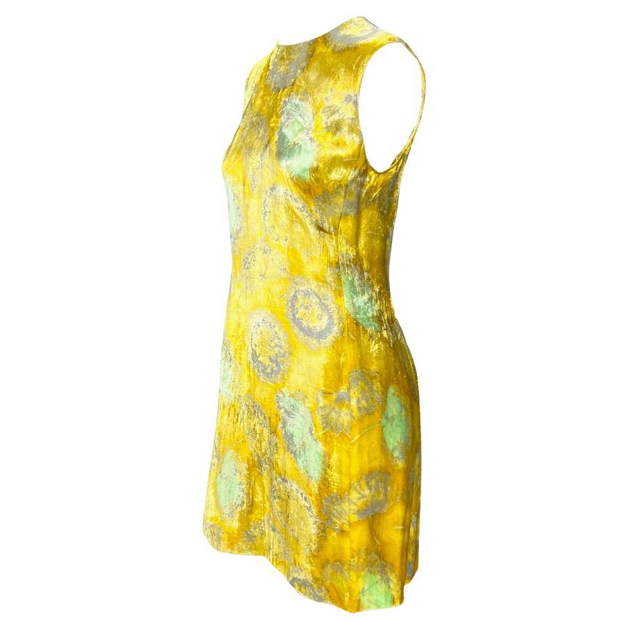 Présentation d'une robe fourreau en velours jaune à fleurs Gianni Versace Couture, conçue par Gianni Versace. Datant de 1997, cette robe lumineuse est entièrement composée d'un jaune vif et de pissenlits verts et gris. Bien qu'elle s'éloigne des