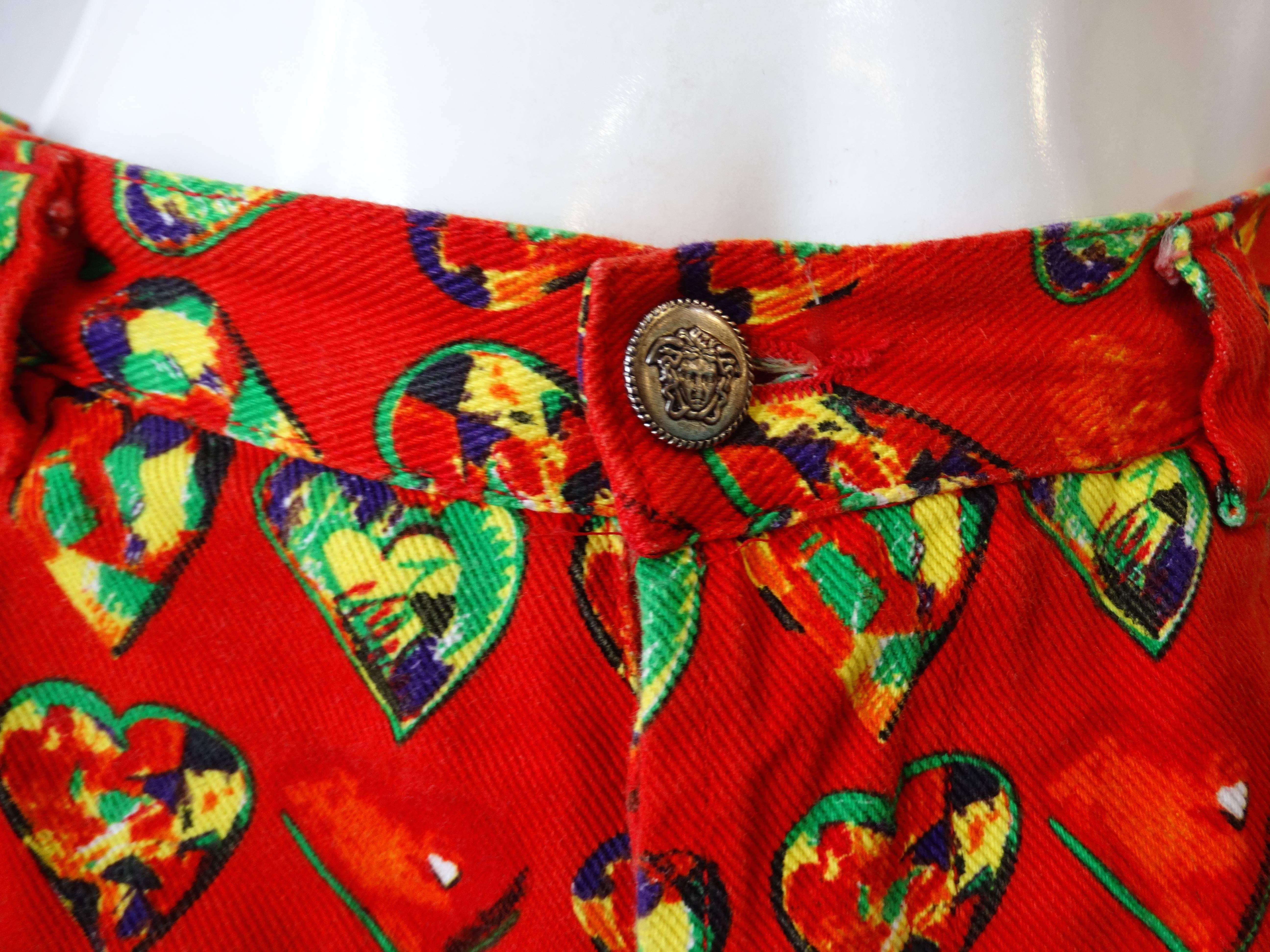 Fall in love with this incredible pair of Versace heart jeans circa 1997! Soft cotton denim material printed with bold red, green and yellow heart pattern! Hidden button fly opens up to reveal a set of silver metal medusa head buttons! Pockets at