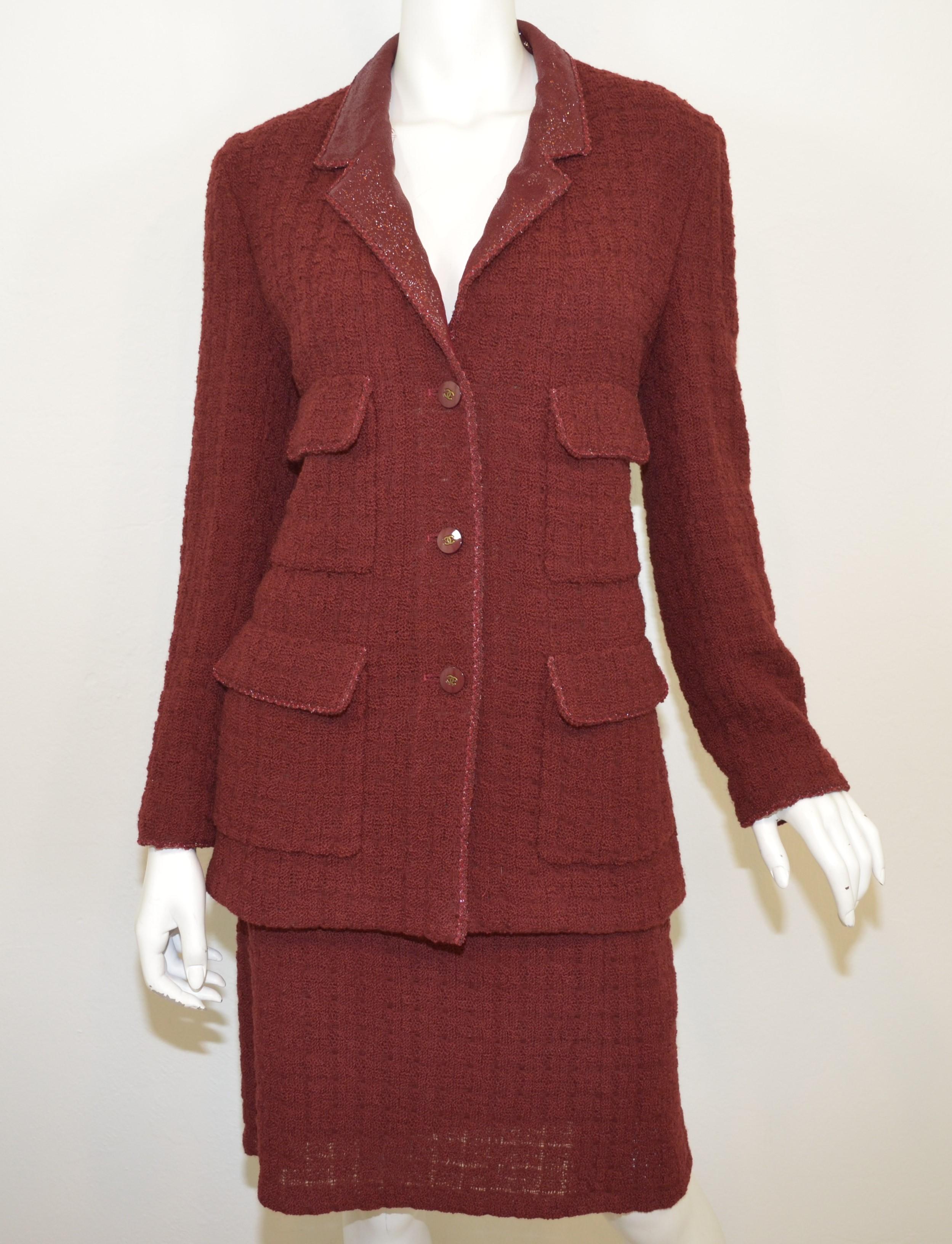 Chanel knitted jacket and skirt set from the 1998 Autumn collection is featured in a maroon color with a shimmering collar and lining to the jacket — Jacket has button closures along the front and along the cuffs of the sleeves. Skirt has a back