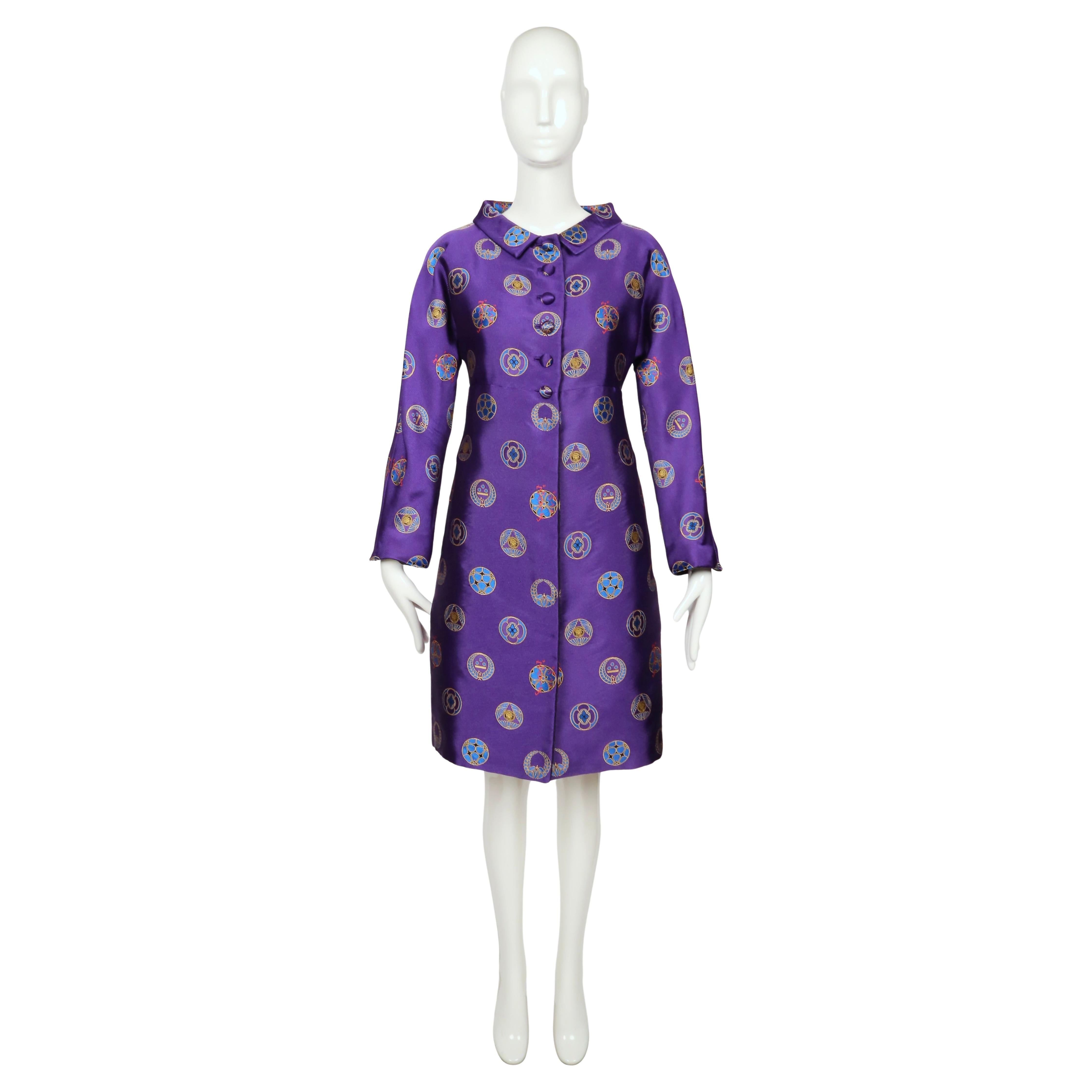 Rarissimo cappotto Atelier Versace della collezione primavera 1998, realizzato in seta viola lucente. La silhouette cade in una sottile linea ad A con un corpetto delicatamente aderente, maniche lunghe e un colletto arrotondato. Una fila di bottoni