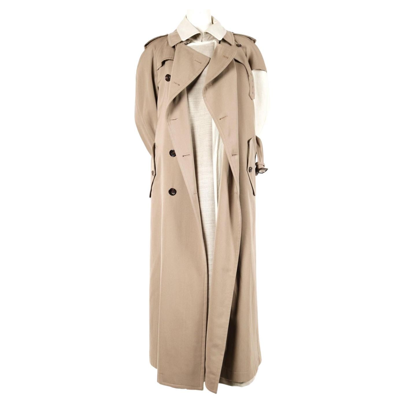 Tan gabardine trench with one arm layered over a wool undercoat designed by Rei Kawakubo for Comme Des Garcons for fall of 1998. Very unusual piece. Similar coats were seen on the runway. Labeled a size 'M'. Due to the oversized cut, this piece fits