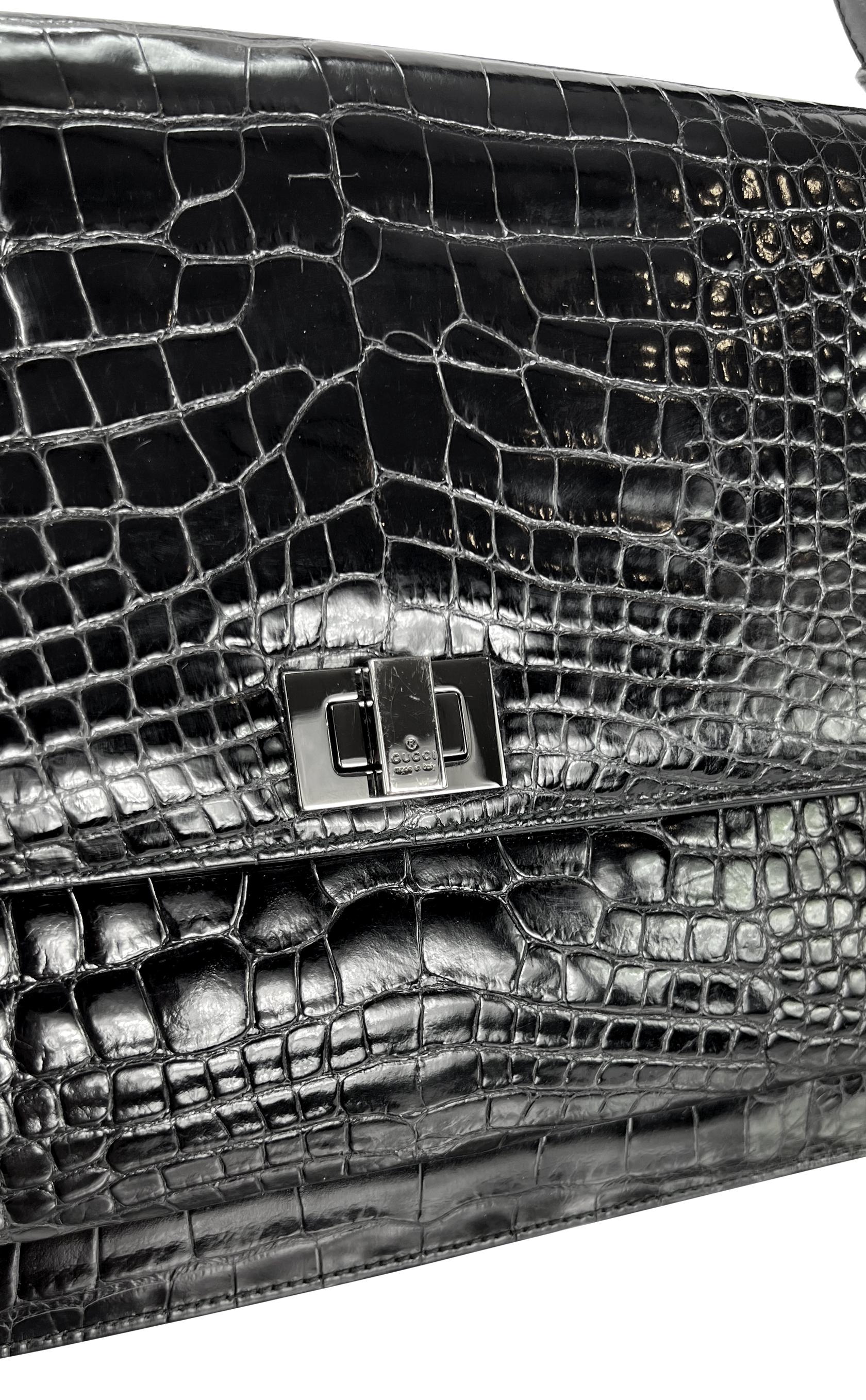 Tom Ford ha disegnato questa splendida borsa a tracolla Gucci in alligatore nero nel 1998. Questa borsa a tracolla piatta è realizzata interamente in pelle di alligatore nera lucida. La borsa è dotata di chiusura con patta, forma rettangolare,