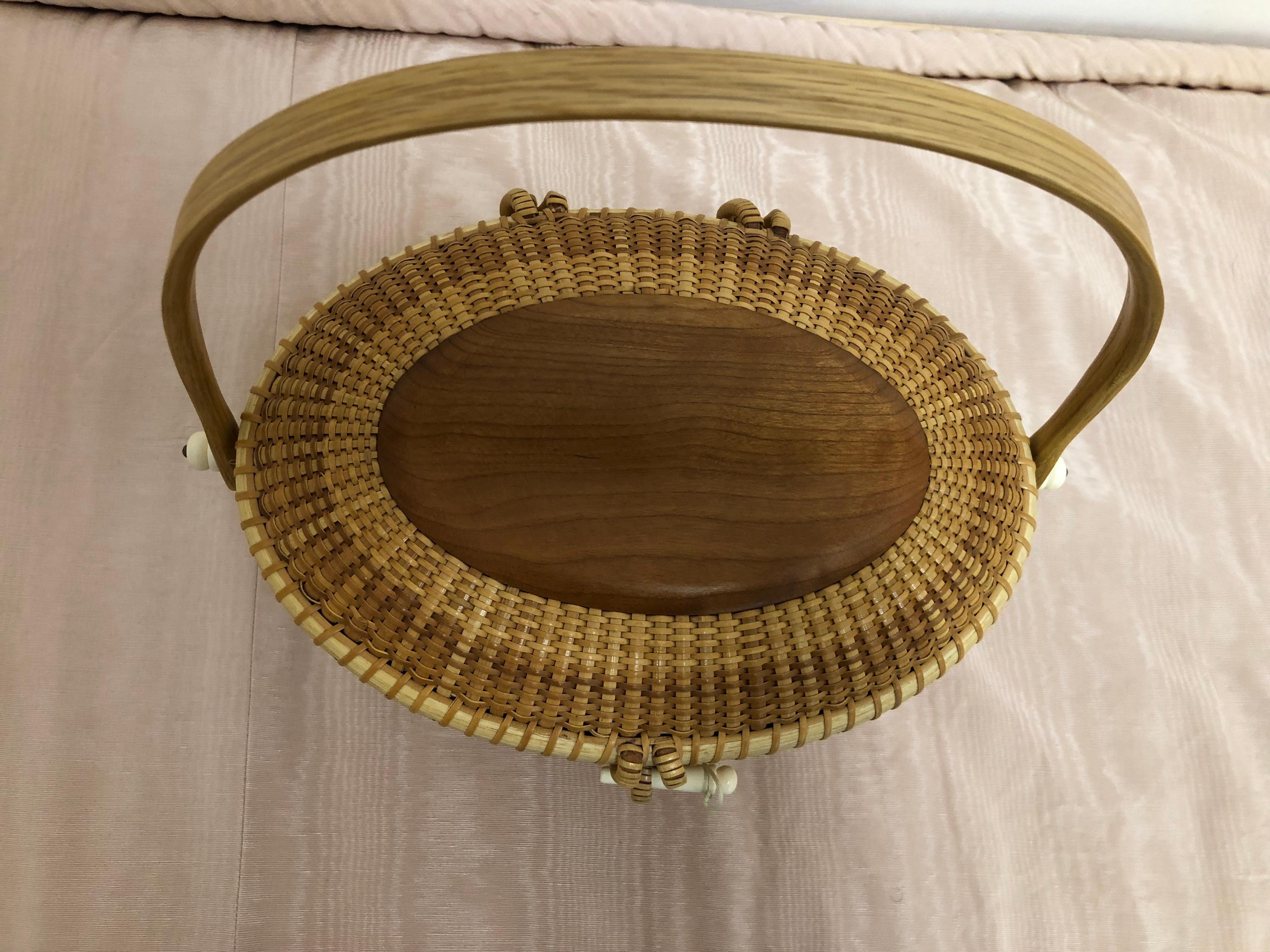 Beautiful tight weaved Nantucket basket with bone embellishments. This basket has never been used and is therefore in as new condition. There is decorative wood oblongs on top and inside, and a nice wood handle. This is truly a collector piece.