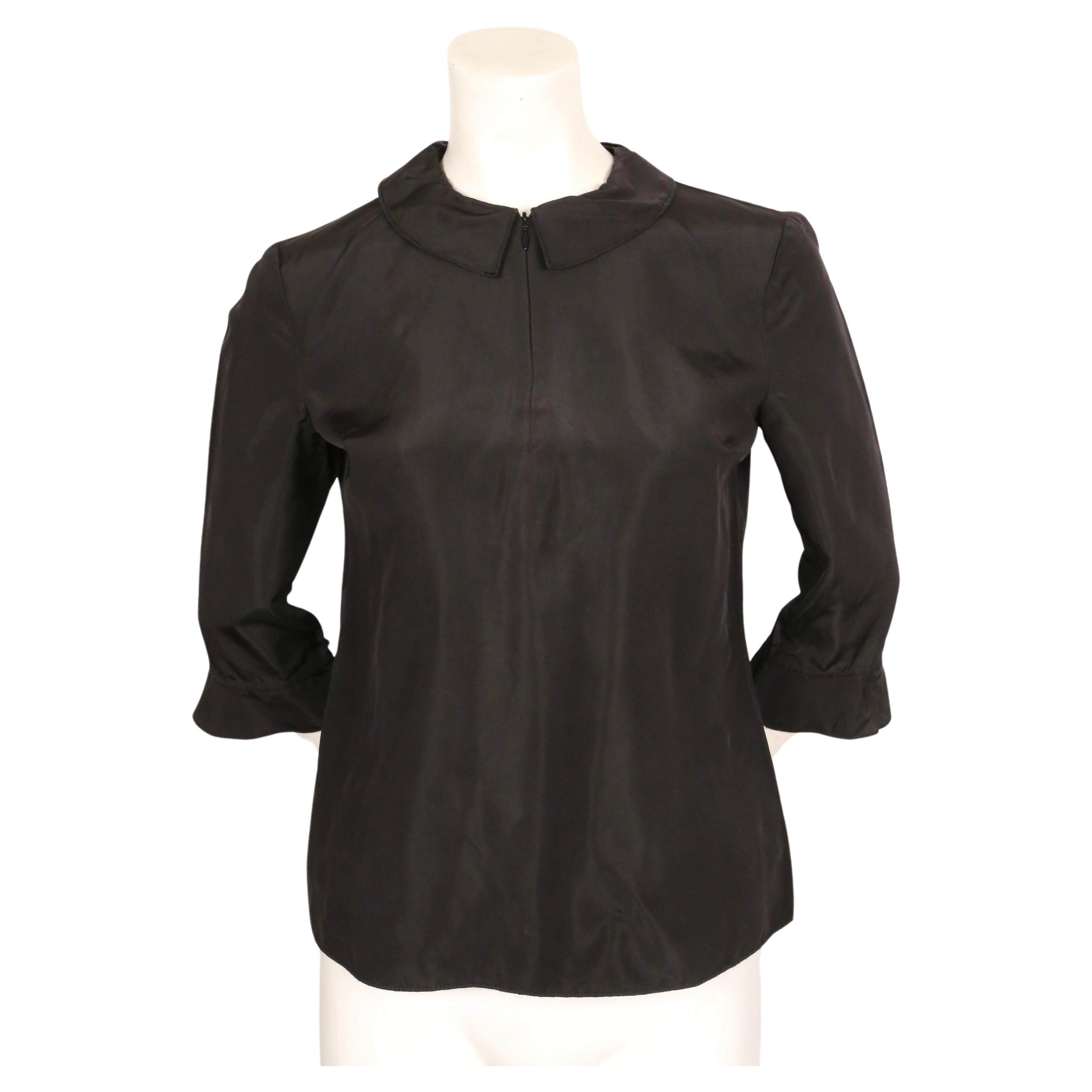 Minimalist black top with ruffled collar and cuffs designed by Miuccia Prada for MIU MIU dating to fall of 1998 as seen on the runway in an alternate color. Labeled a size 40. Approximate measurements: shoulder 15