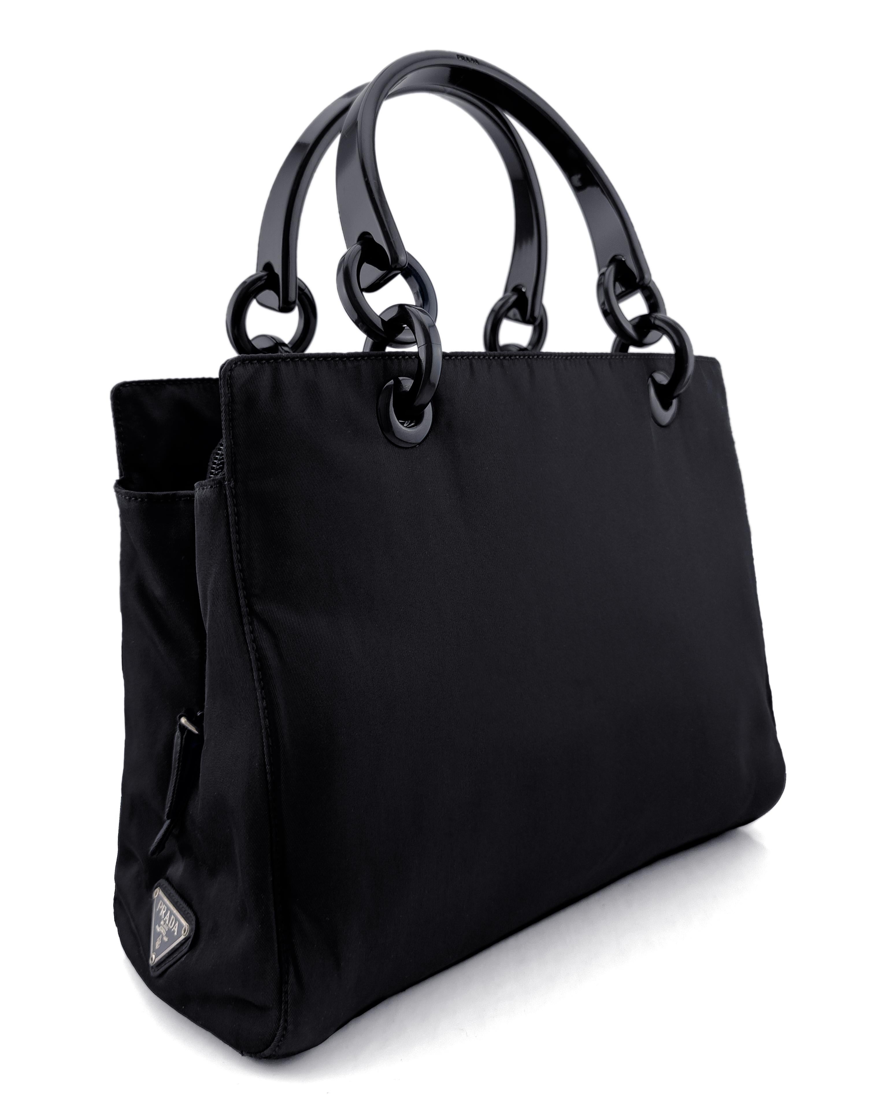 Zeitlose kleine Prada-Tasche aus dem Jahr 1998. Klassische Prada Tasche aus strapazierfähigem schwarzem Nylon mit schwarzen Kunststoffringen und doppelten Henkeln. Äußerst funktionell mit drei großen Innenfächern. Das linke und das rechte Fach sind