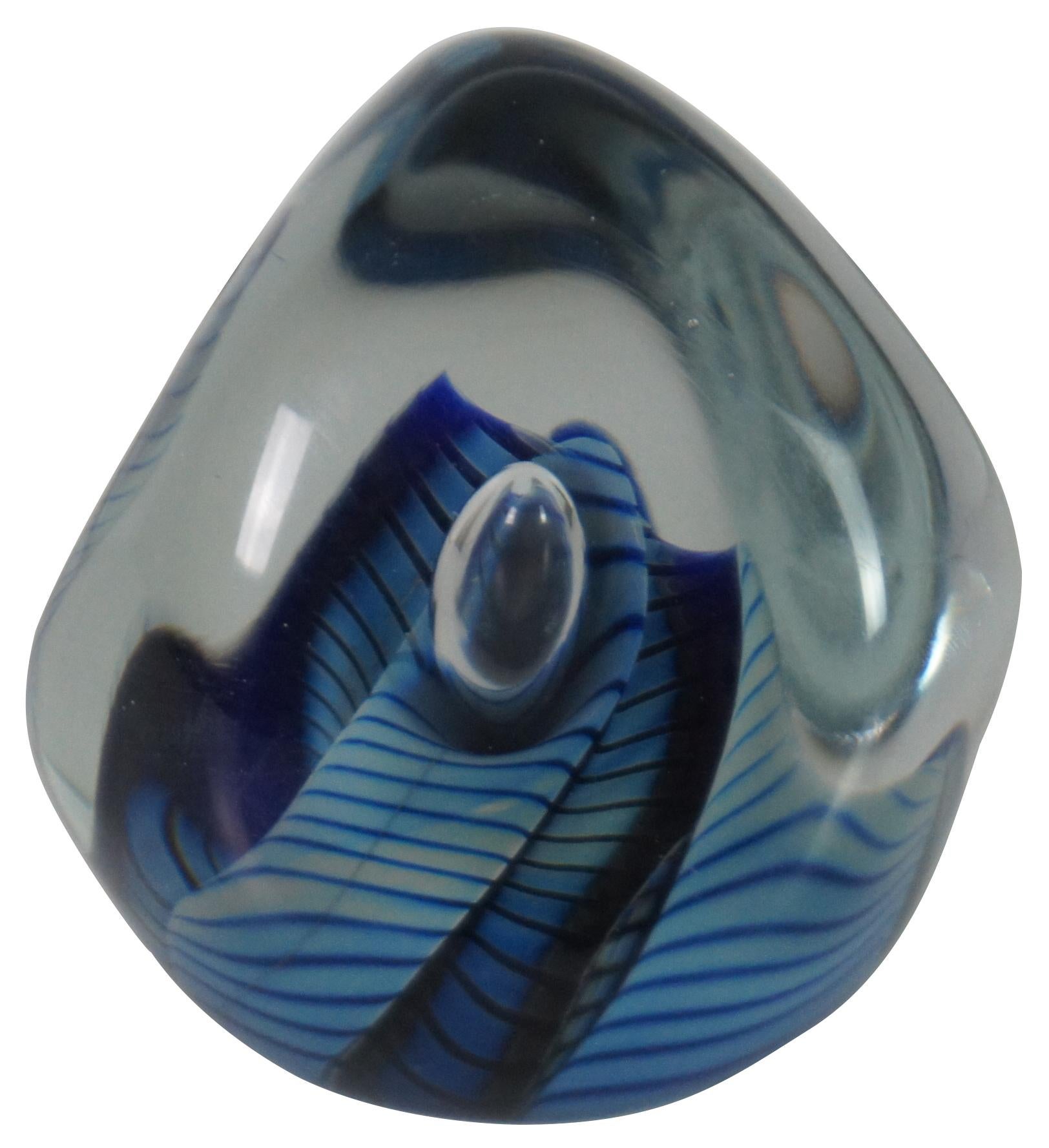 Vintage Robert Eickholt studio art glass paperweight featuring a clear abstract form filled with rippling stripes in various shades of blue and a large controlled bubble at the center. Signed and dated 1988 on base.

Robert Eickholt is a well