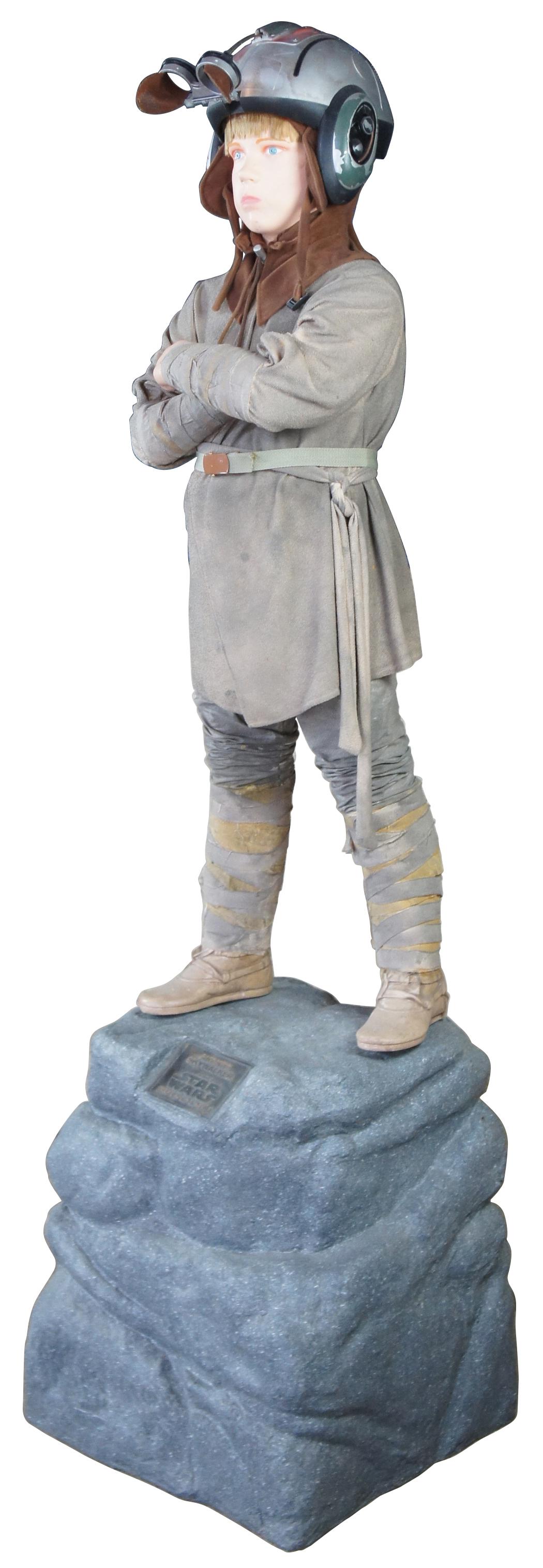 Life size fiberglass prop of Anakin Skywalker from Star Wars Episode 1. Features Lord Vader as a youth in his pod racing outfit with articulating goggles standing cross arm atop a boulder. Displayed at JC Penney and given away as a raffle promotion