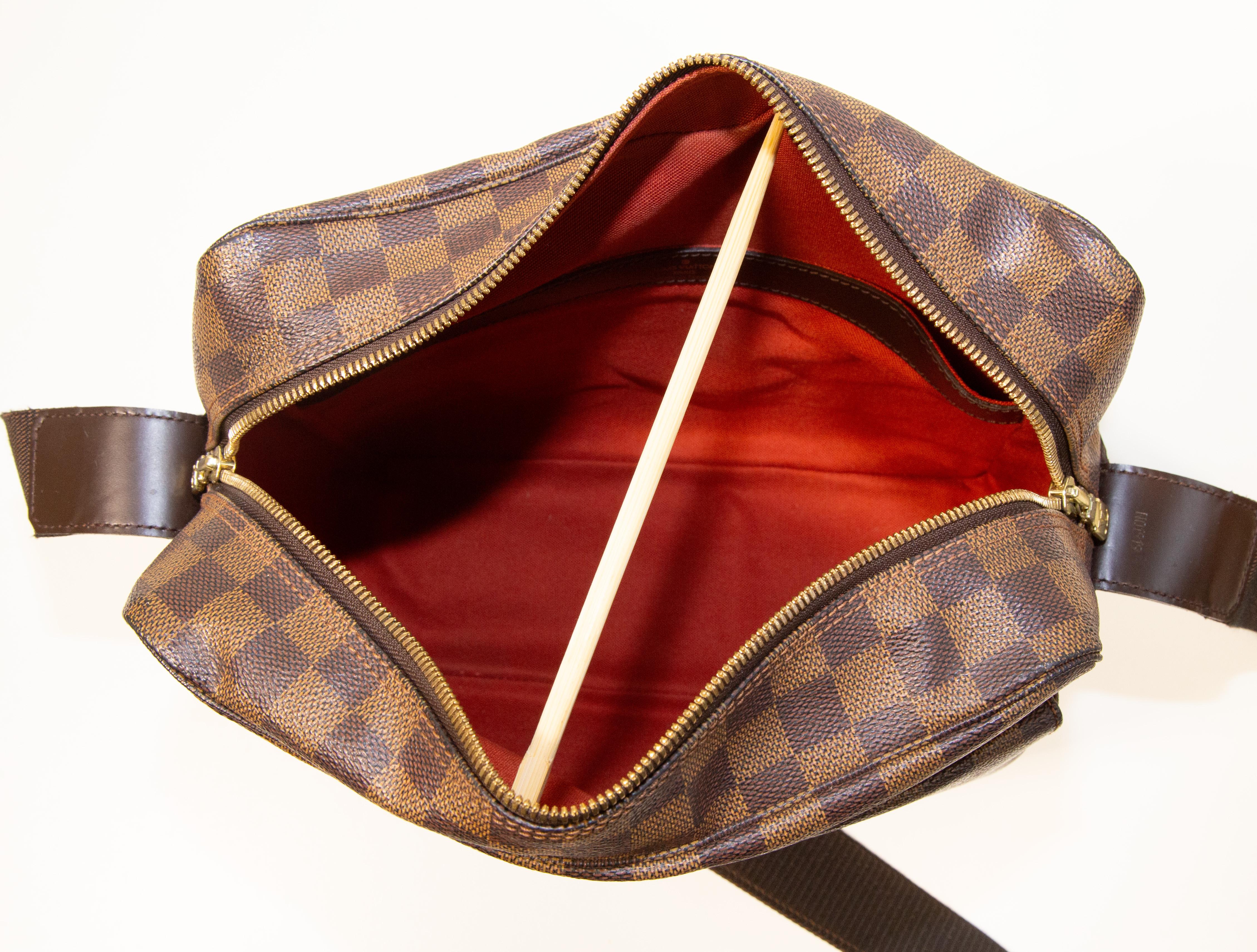 Louis Vuitton Naviglio shoulder bag made of coated canvas with Damier Ebene pattern, brown leather finish, and brass-colored hardware. The inside is lined with red canvas and in addition to the main compartment, it has one side pocket. There are