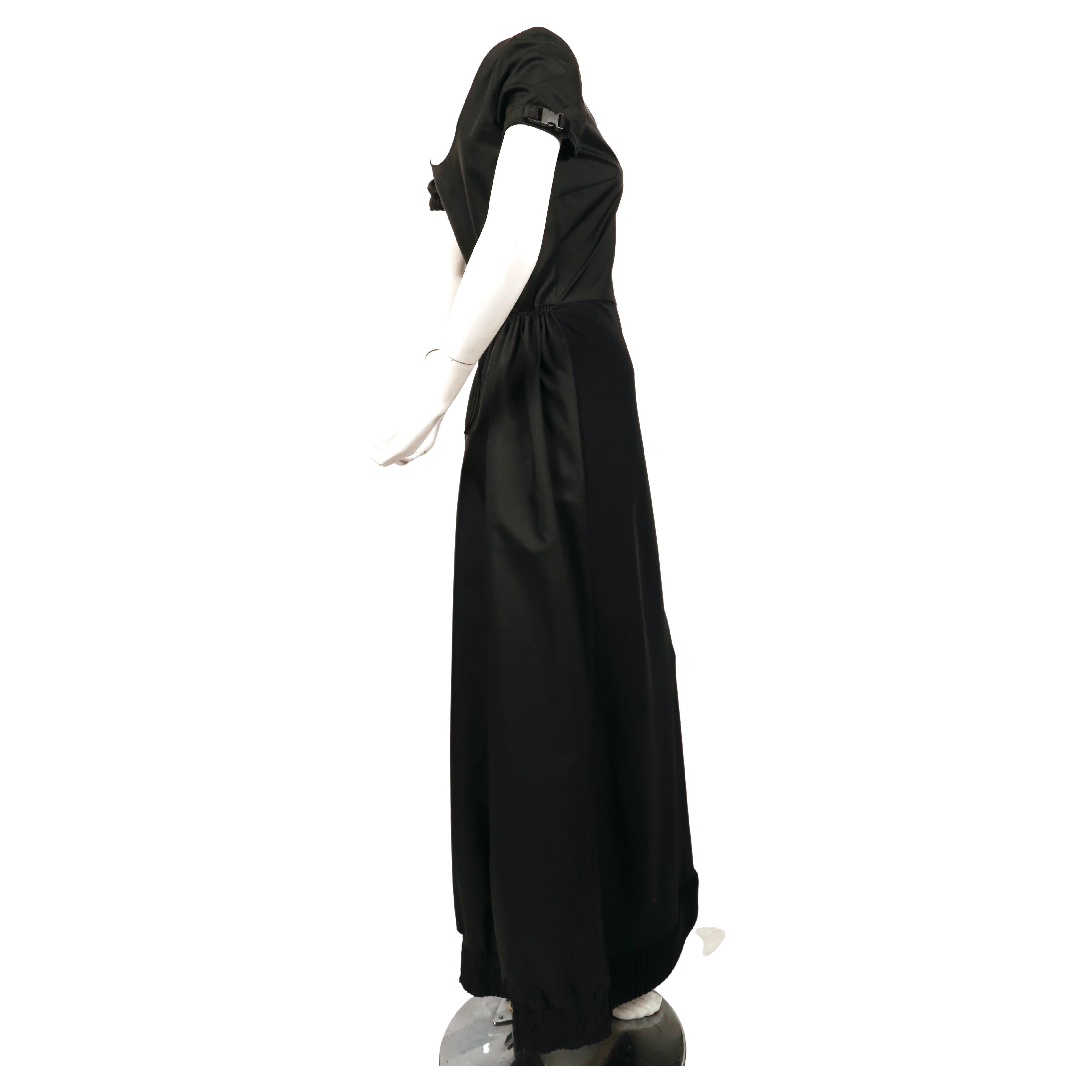 Jet-black, nylon and scuba gown with ribbed knit hemline, buckle details at sleeves and cinched waist designed by Miuccia Prada exactly as seen on the MIU MIU runway for fall of 1999. Labeled a size 42 however this fits small and would best fit a US