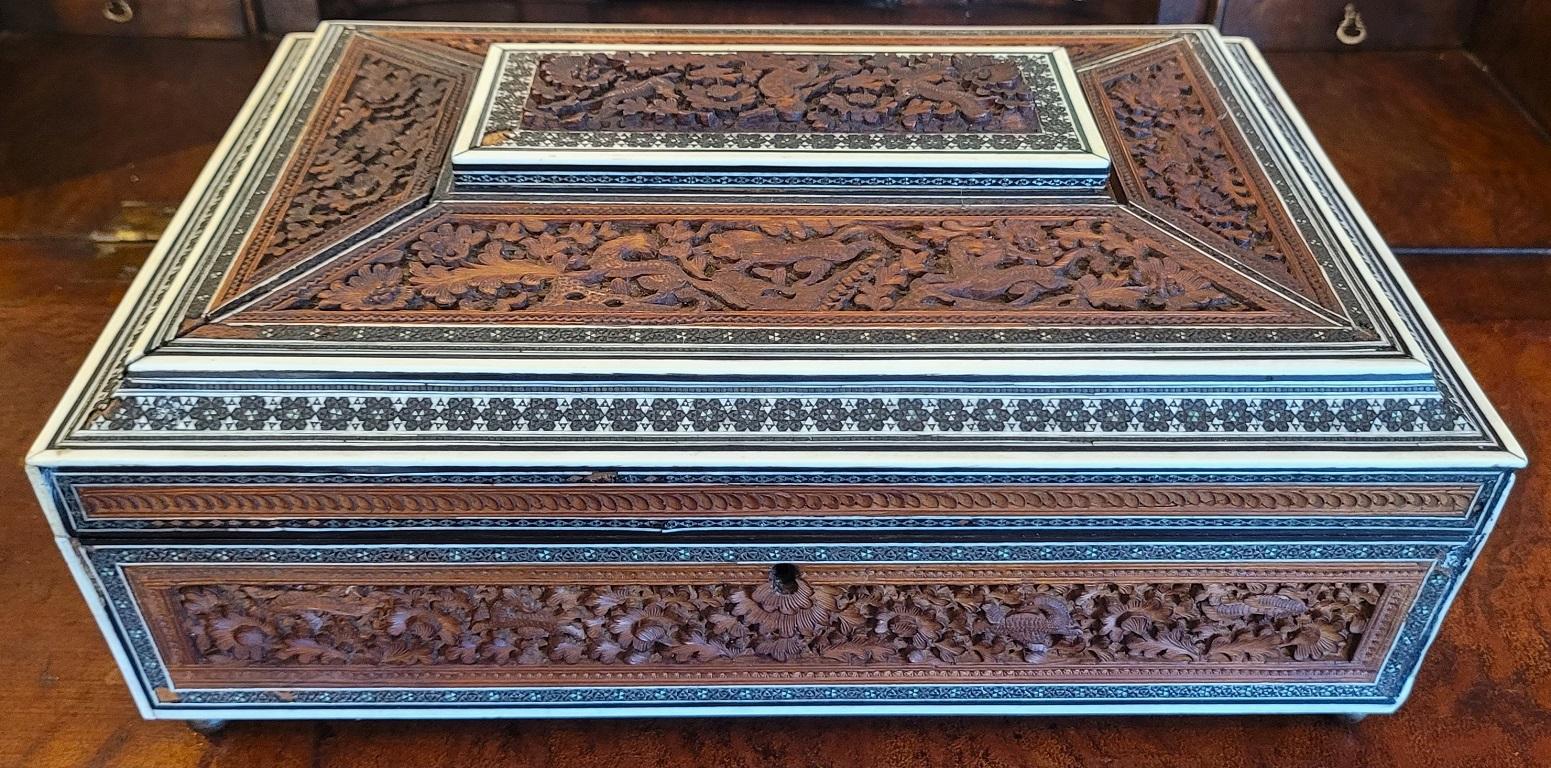 PRESENTING A GORGEOUS 19C Anglo Indian Highly Carved Padouk and Sandalwood Sadeli Mosaic Sarcophagus Sewing Box.

Made in Bombay, India circa 1860-80.

Box made of sandalwood with highly carved padouk wood reliefs and panels on all