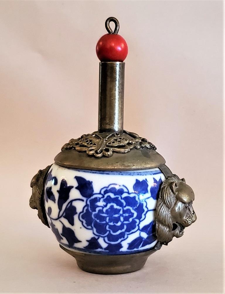 Gorgeous little Tibetan pewter/brass mix and blue and white porcelain snuff bottle from circa 1870-1890, late Qing Dynasty.

The quality of the silver casting is superb.

The bottle is flanked by 2 lions heads, both beautifully cast.

The top