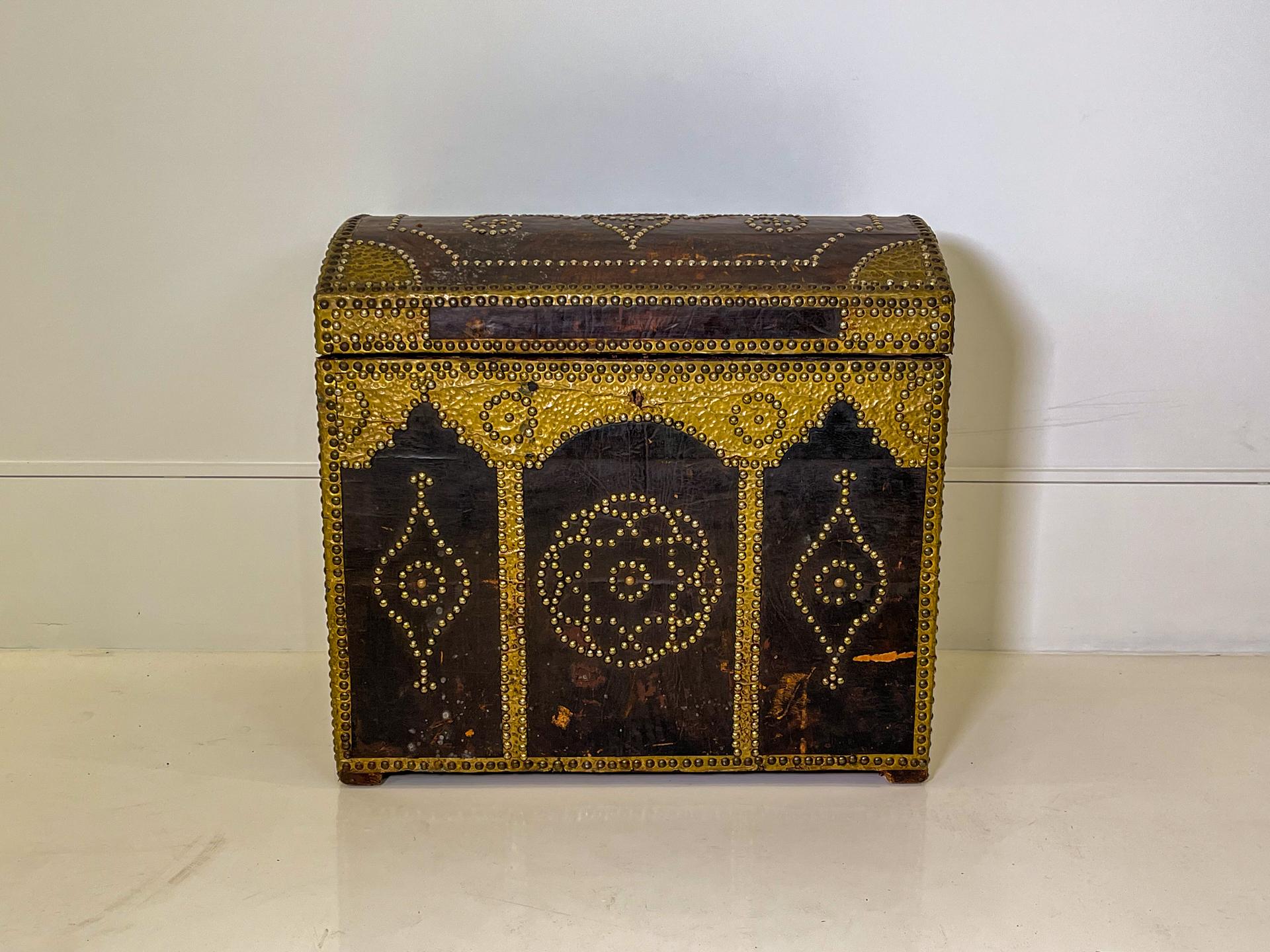 This is a medium sized chest that would be comfortable on the floor or on a table. Coffee Colored leather is extravagantly embellished with brass appliqués and nail heads.