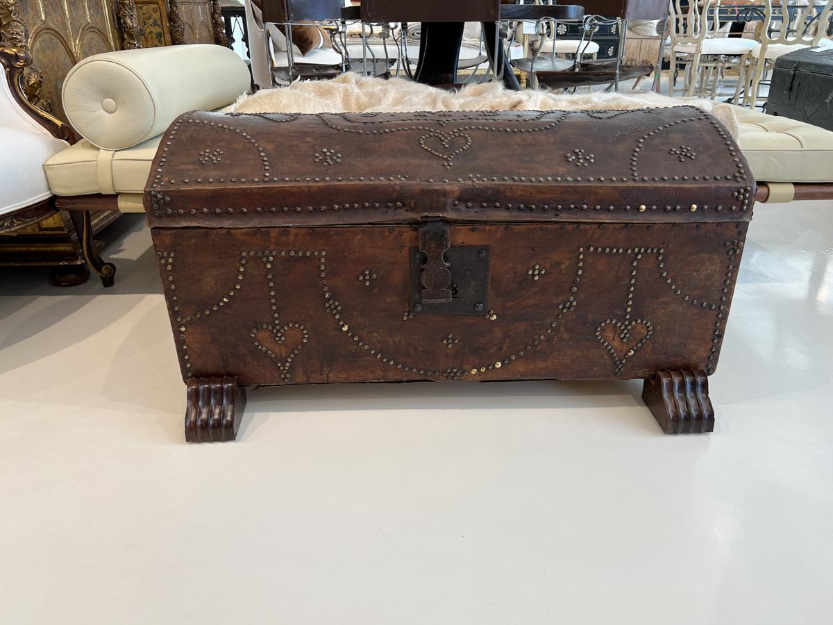 Brown leather trunk on stand with nailhead embellishments. Monogram on top is JMB.