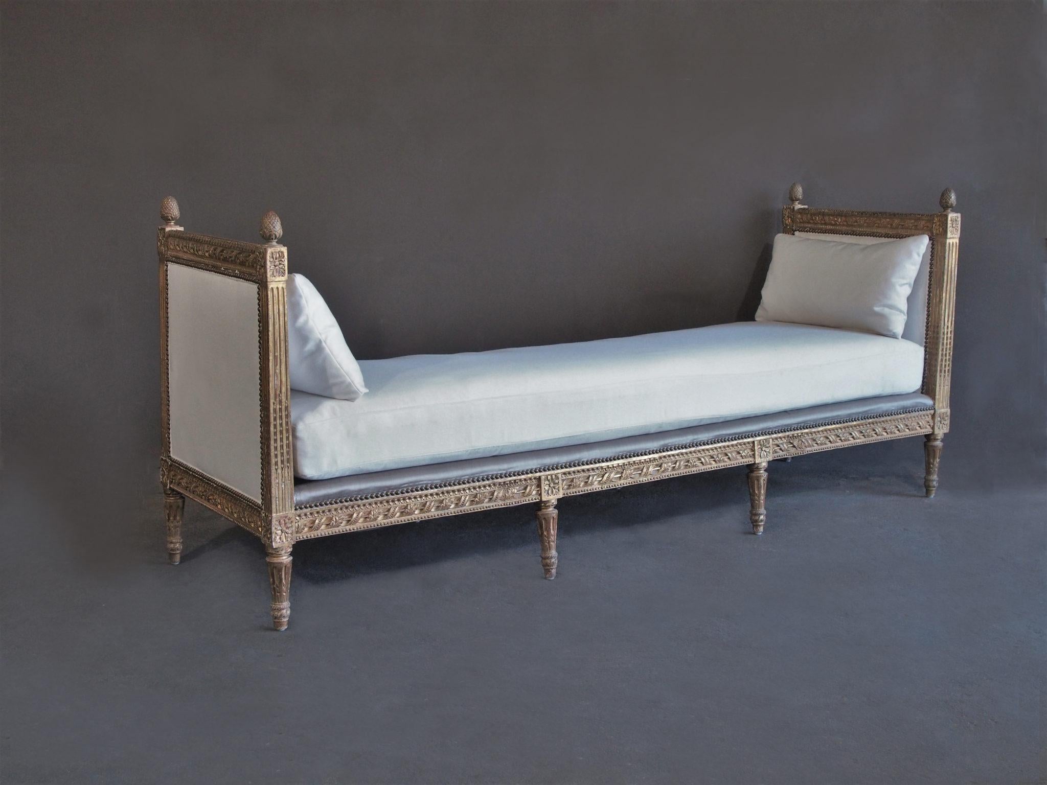 19th century French Louis XVI upholstered daybed. Beautiful as a sofa or simply as a place to relax. Finely carved framework – fluted and floral carving with detailed finials. Upholstery in heavy weight white Belgian Linen on mattress and on the end