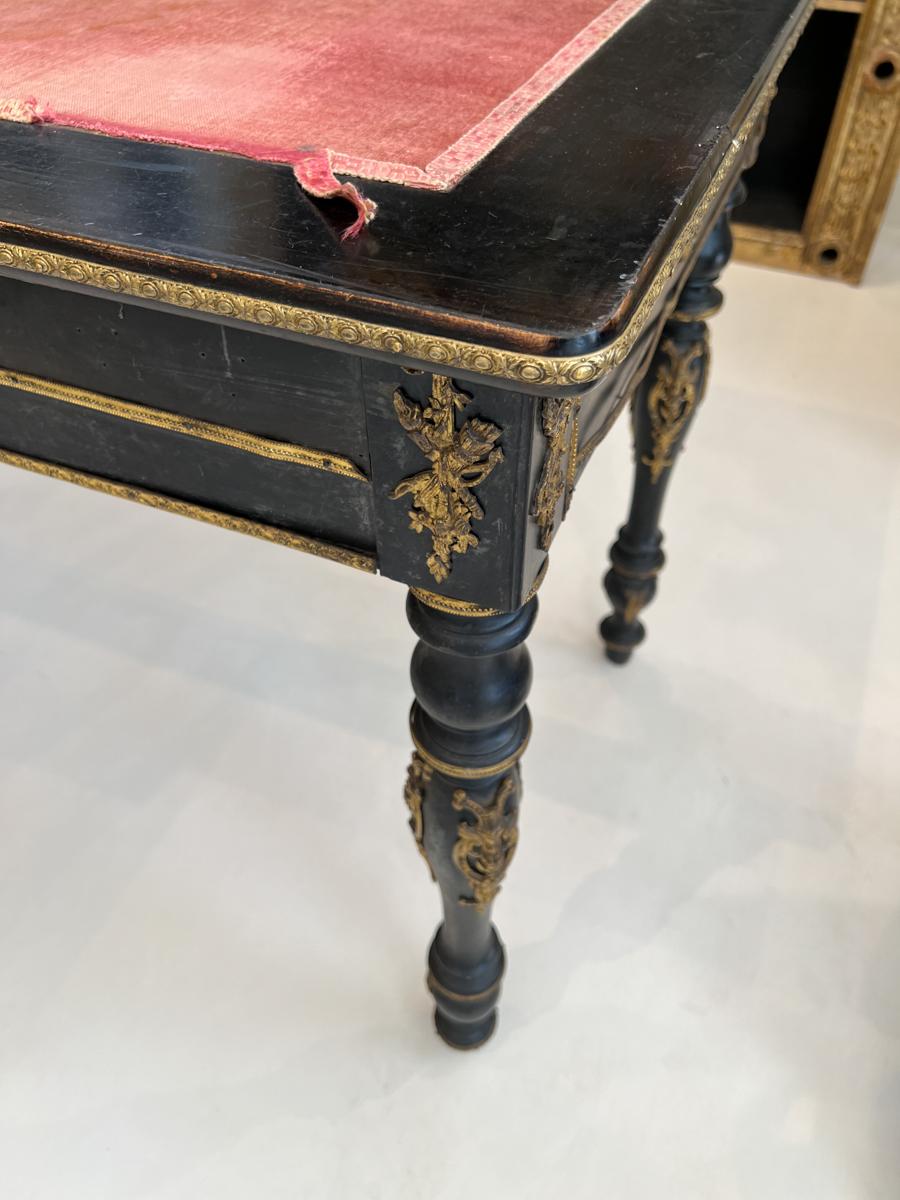 Beautiful black desk with red felt top and generous application of gold ormolu on drawers and legs.