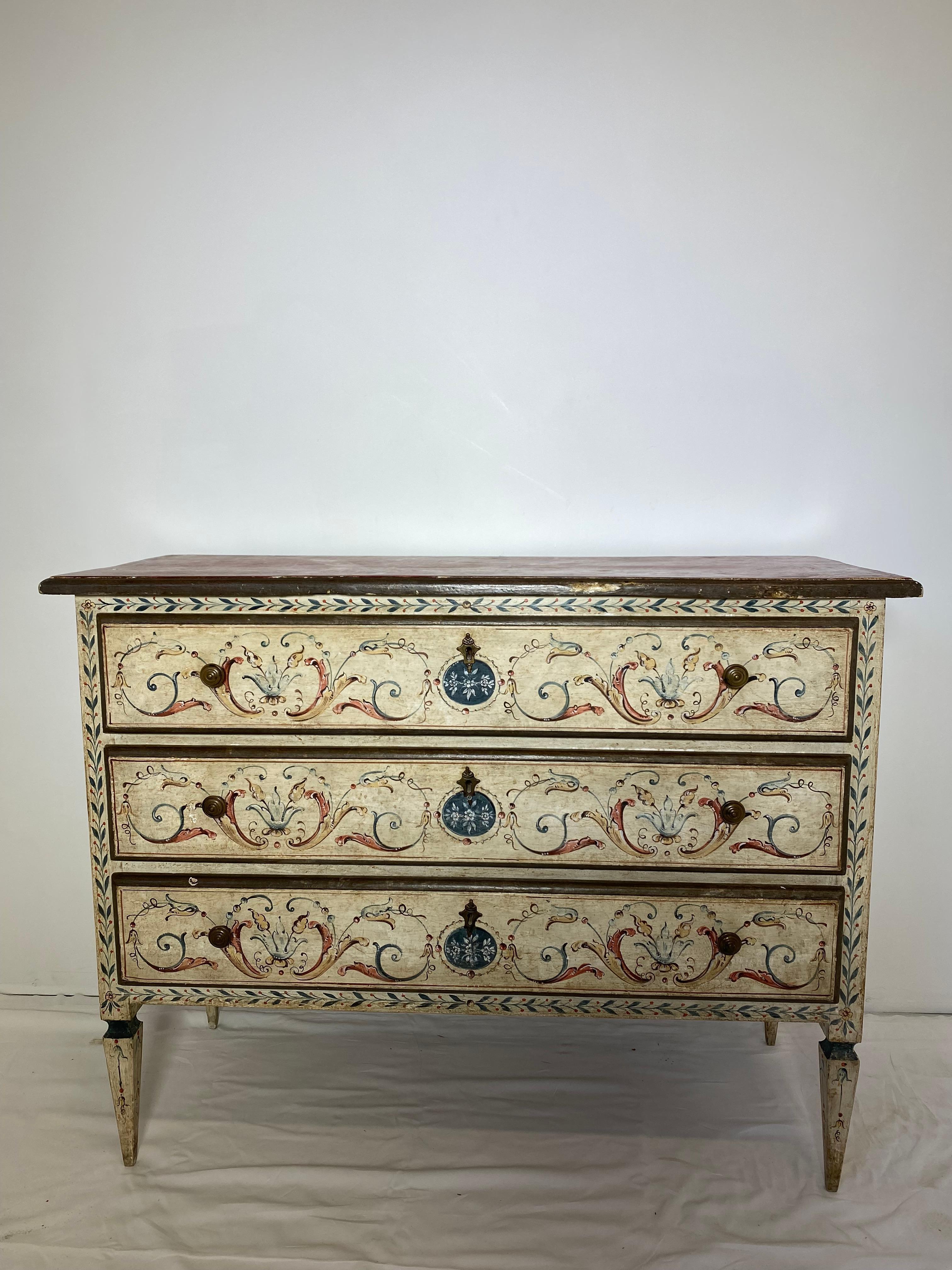 19th century painted Italian commode. An Italian polychrome faux-marble top neoclassic commode 19th century the faux-marble top above three drawers all resting on tapering legs. Decorated throughout with great detail.
